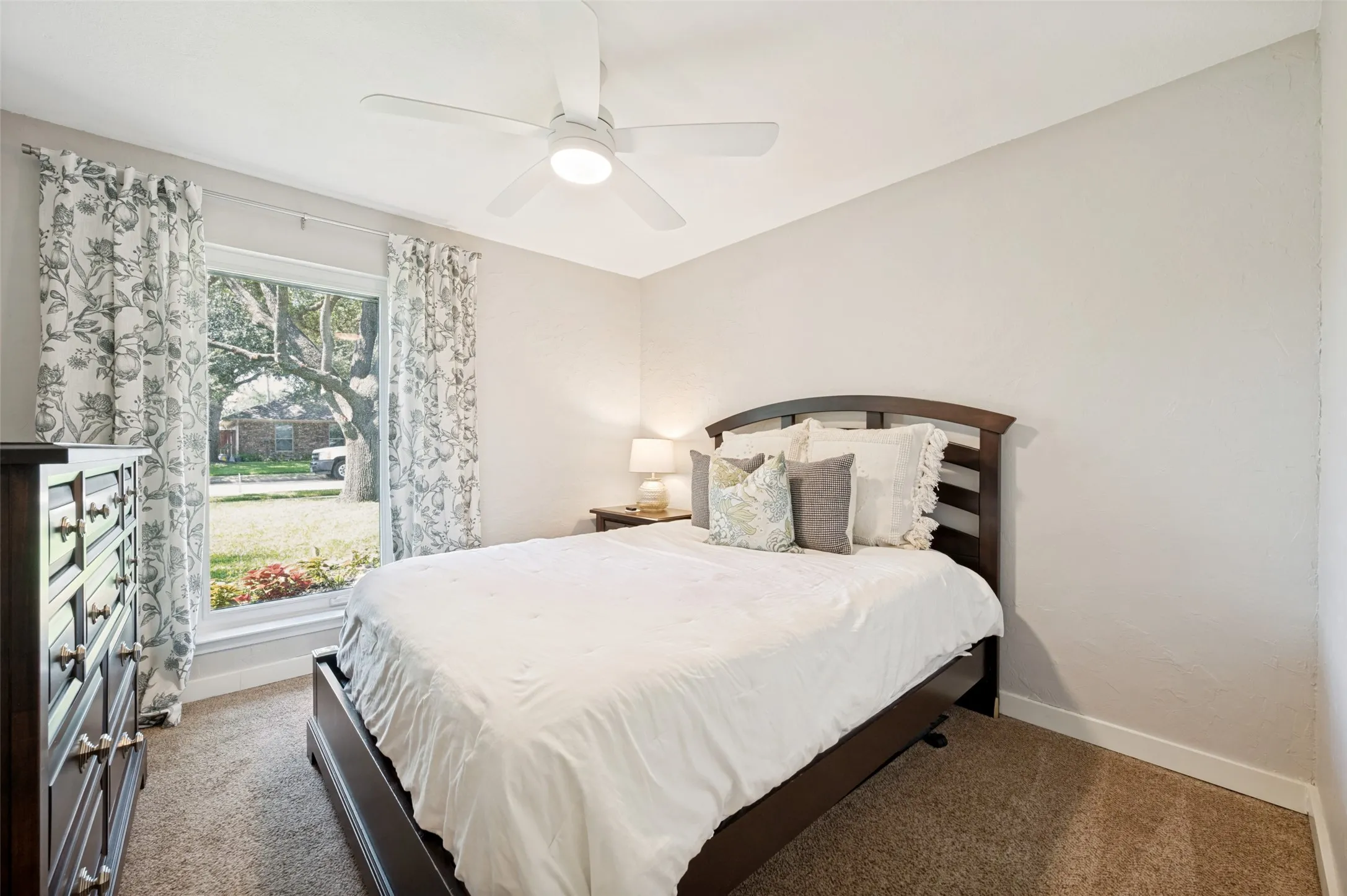 2nd Bedroom with ceiling fan, light-colored walls, carpet flooring, and window with exterior landscaping views - makes for lovely Guest quarters.