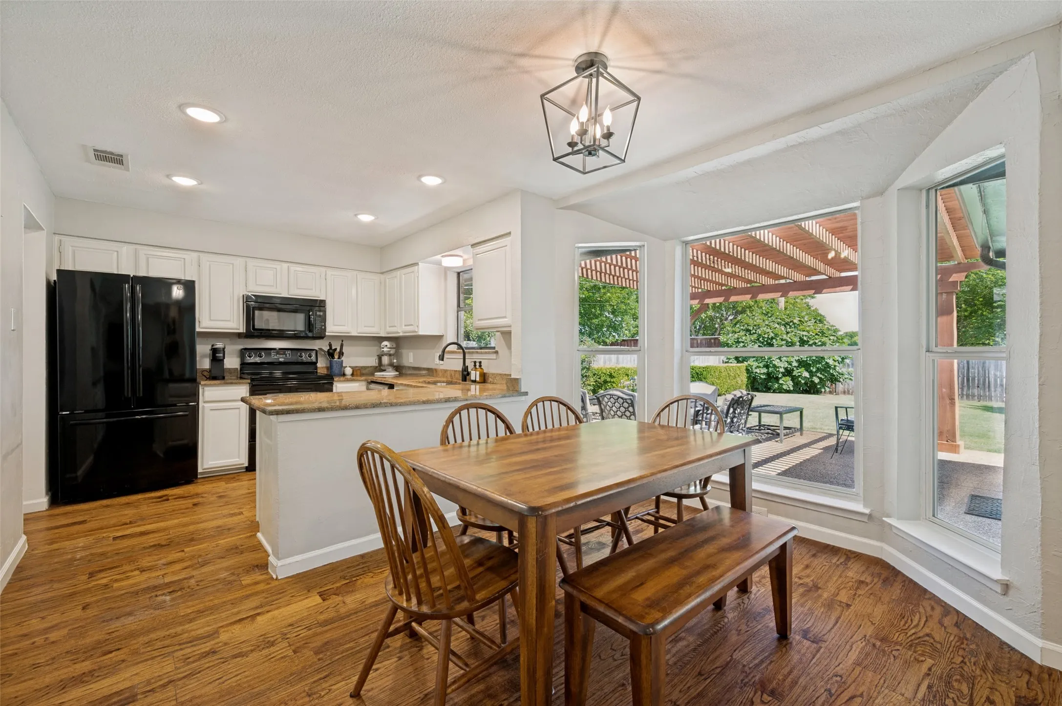 Eat-in kitchen showcases the wood flooring, white cabinetry, and granite countertops