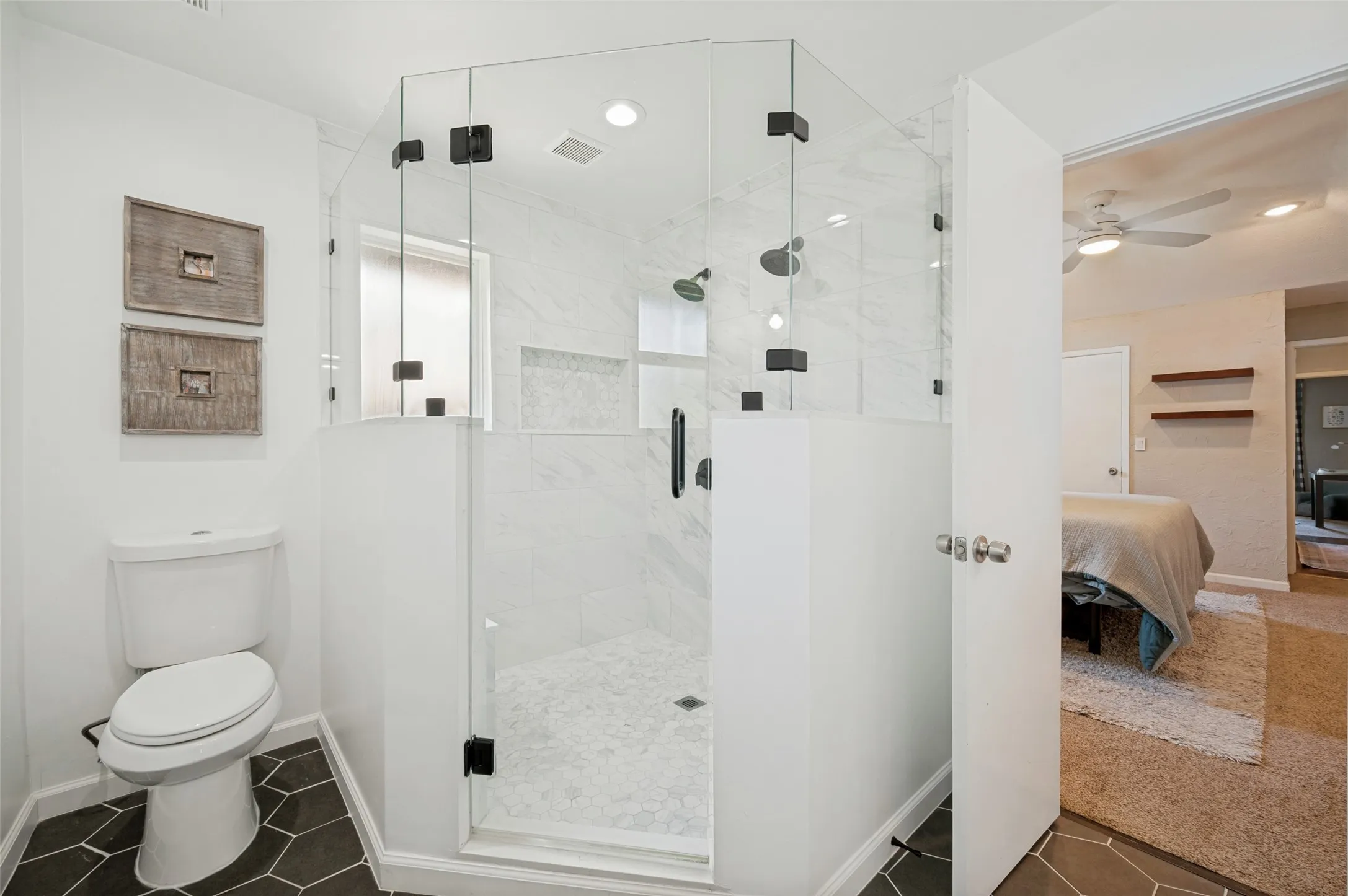 Glass-enclosed shower with black hardware, white subway tile surround, and hexagonal floor tiles