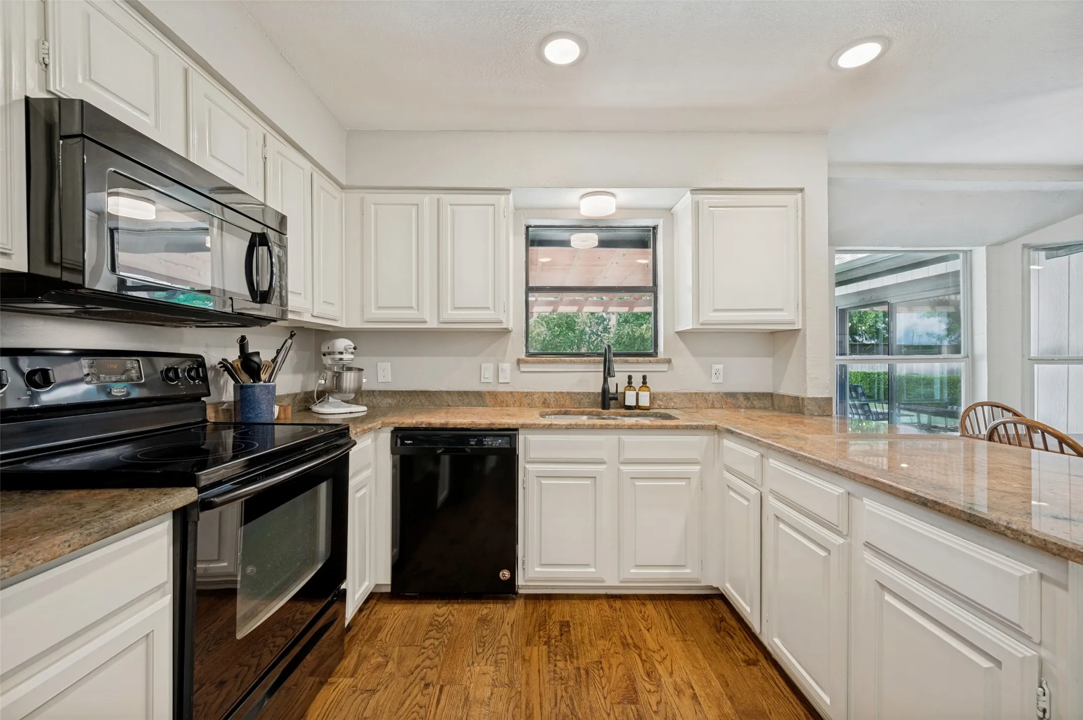 Black appliances accent the modern kitchen cabinetry and contrast beautifully with the Granite countertops.