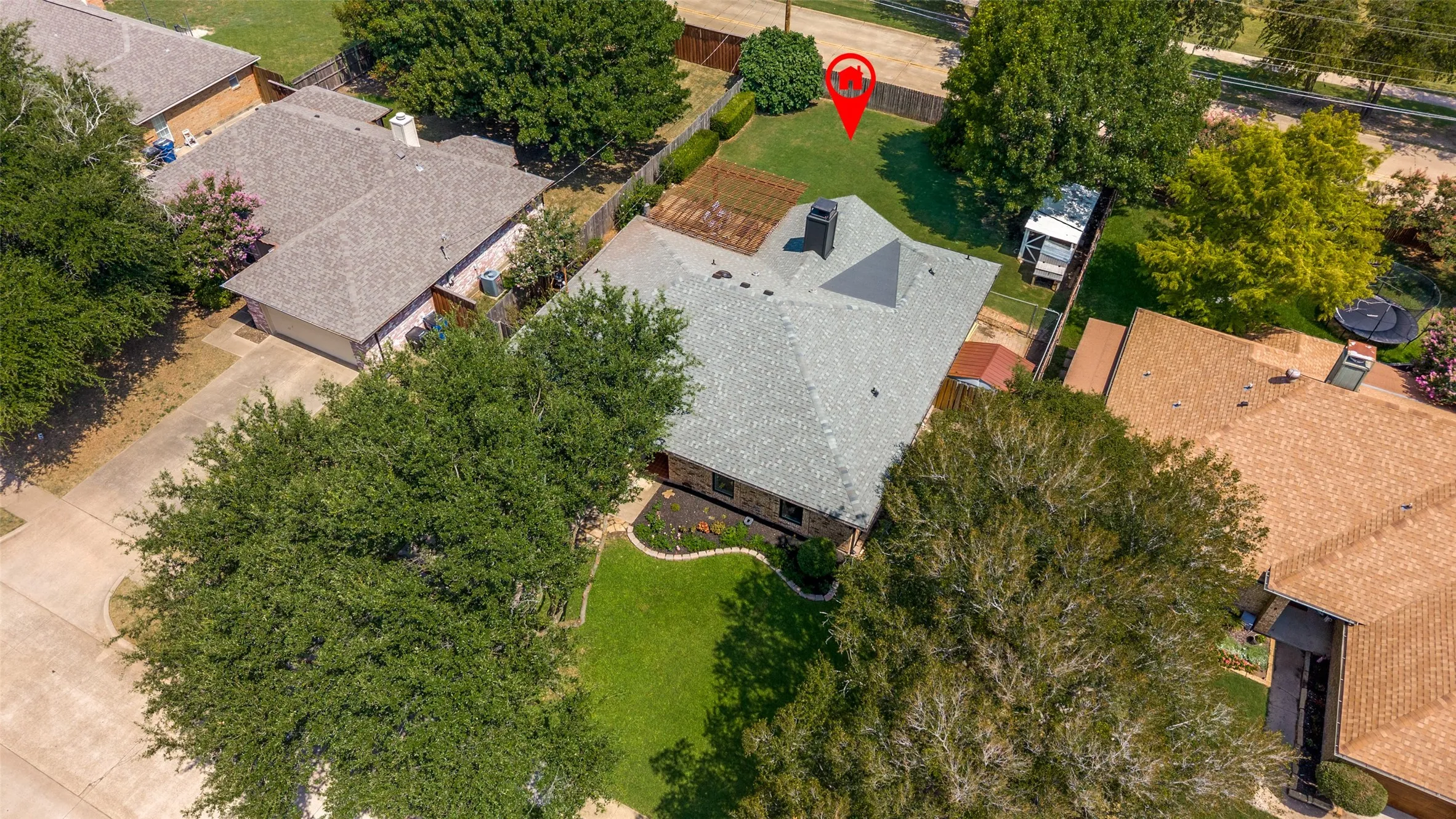  View of new gray roof, established landscaping, a backyard shed, and a privacy fence