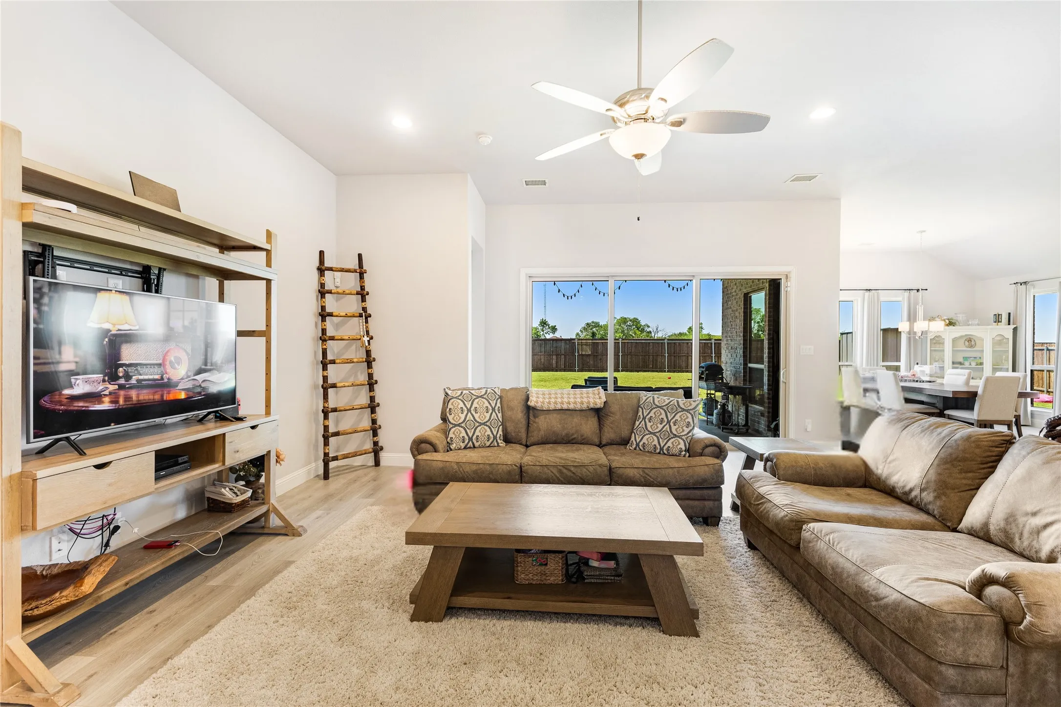 Expansive living area with wood-finish flooring, recessed lighting, and a ceiling fan