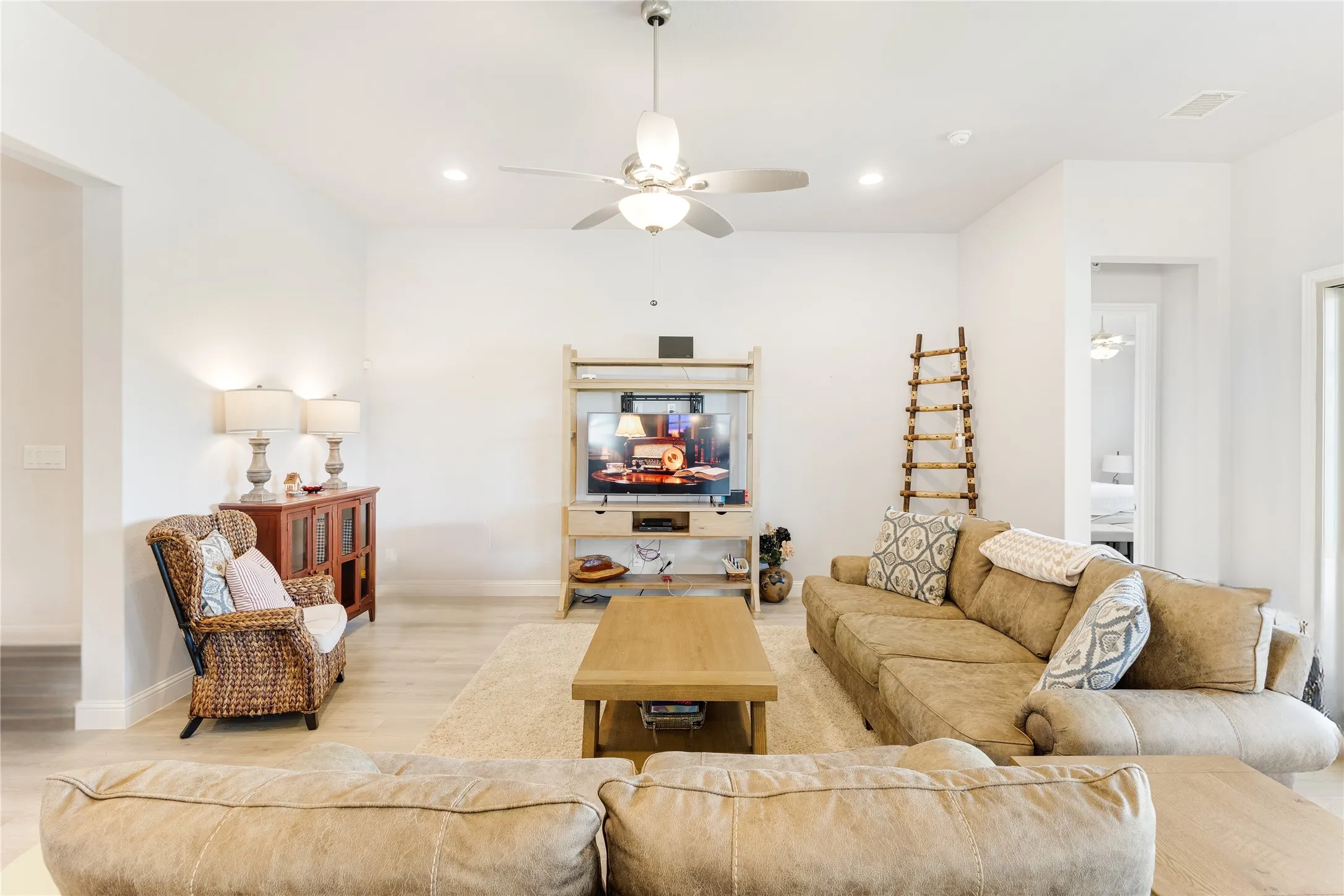 Spacious living area featuring light wood-finish flooring, recessed lighting, a ceiling fan, and white baseboards