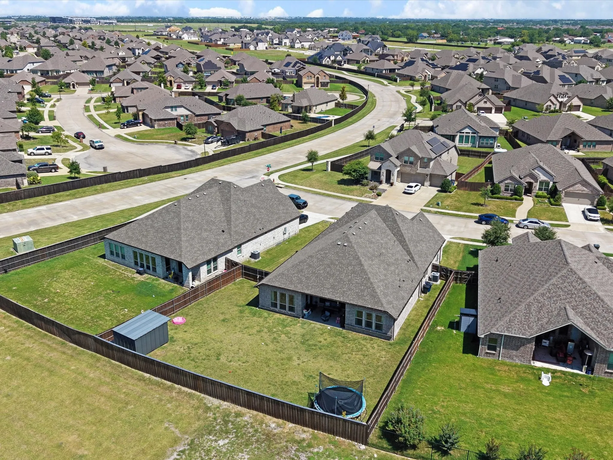Aerial perspective of a residential neighborhood featuring multiple single-story homes with shingled roofs and private fenced backyards