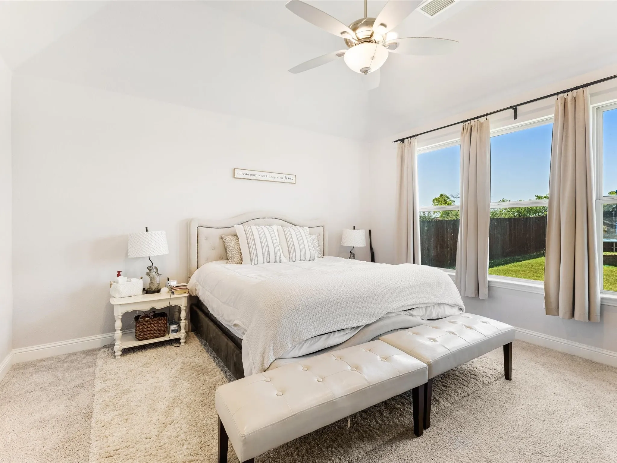 Bedroom featuring a vaulted ceiling with a ceiling fan, three windows with black curtain rods, and neutral-toned carpeting