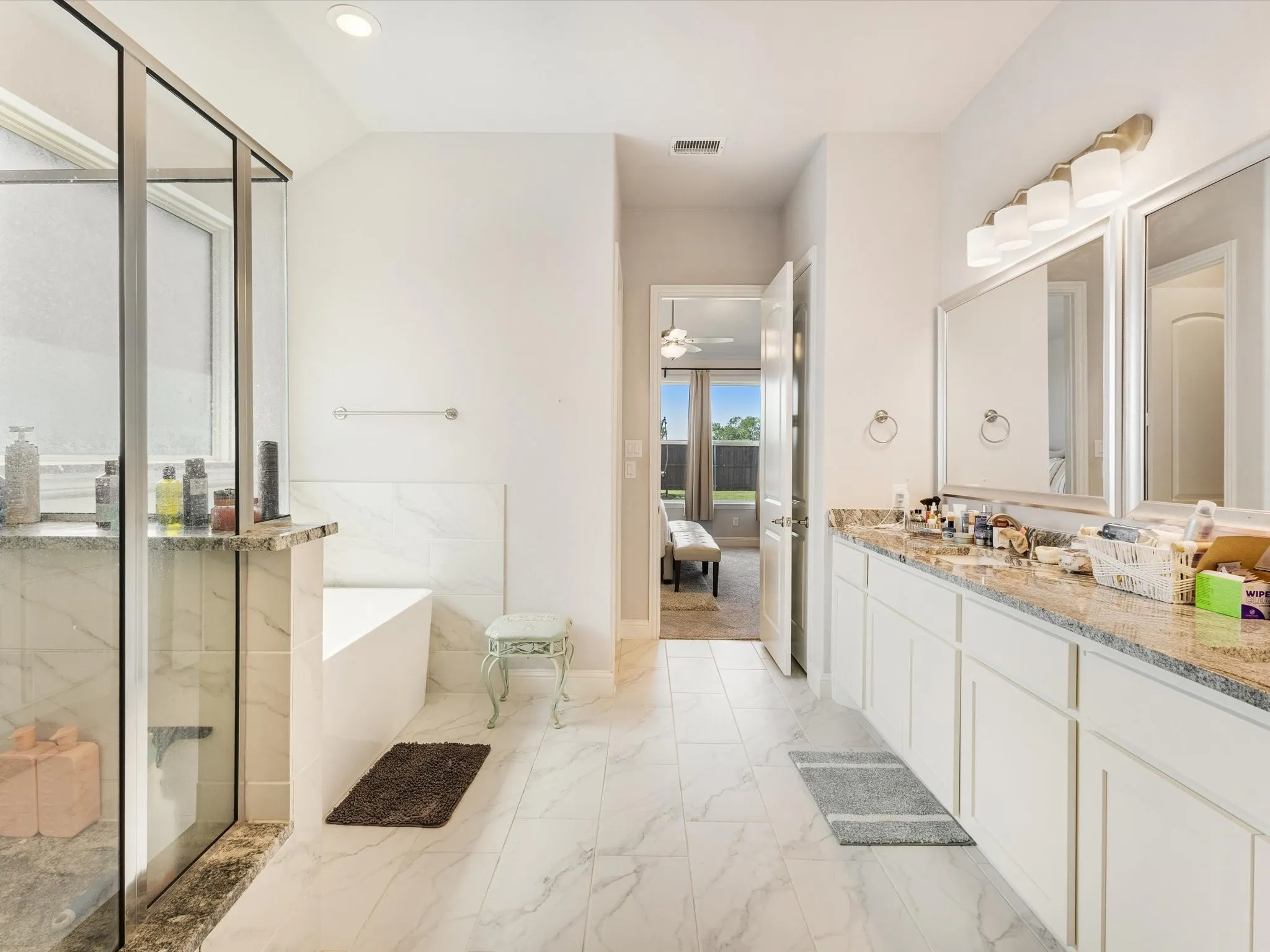 Spacious bathroom featuring a frameless glass shower enclosure, a separate soaking tub, and dual vanity sinks