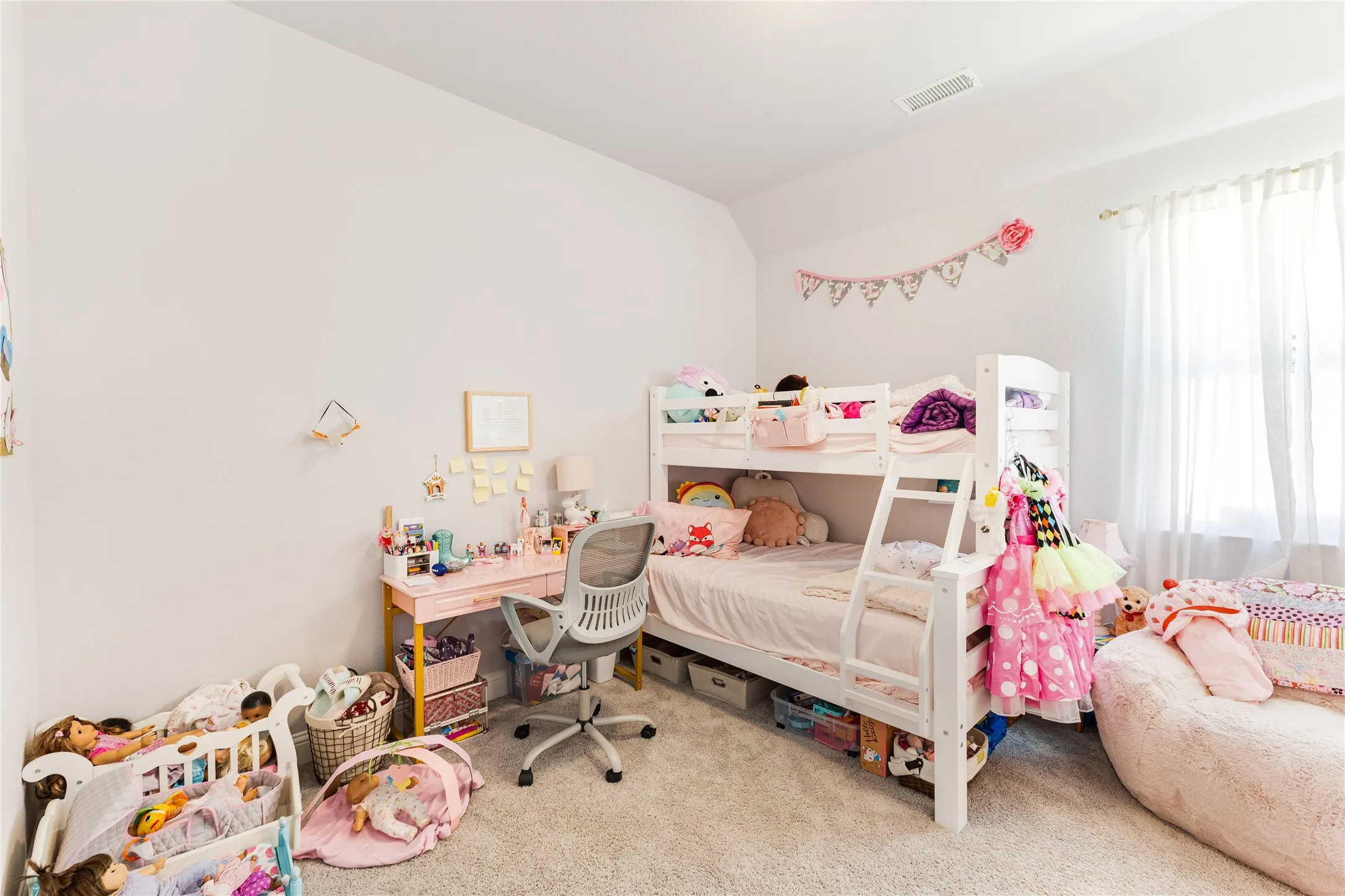 Carpeted room featuring a window with sheer white curtains, white walls, and a recessed ceiling vent
