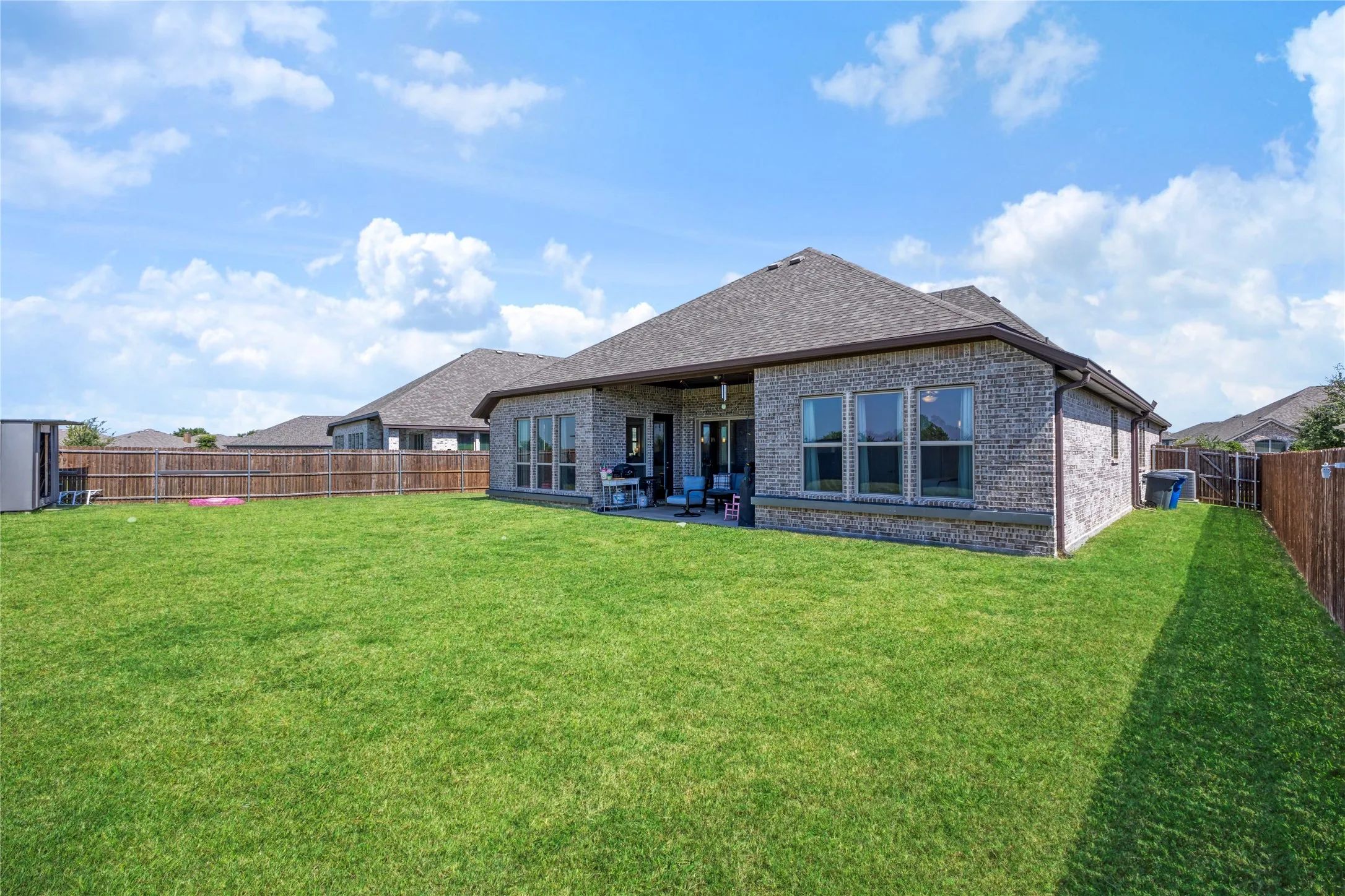 Expansive green lawn surrounds a brick and stone exterior with multiple windows