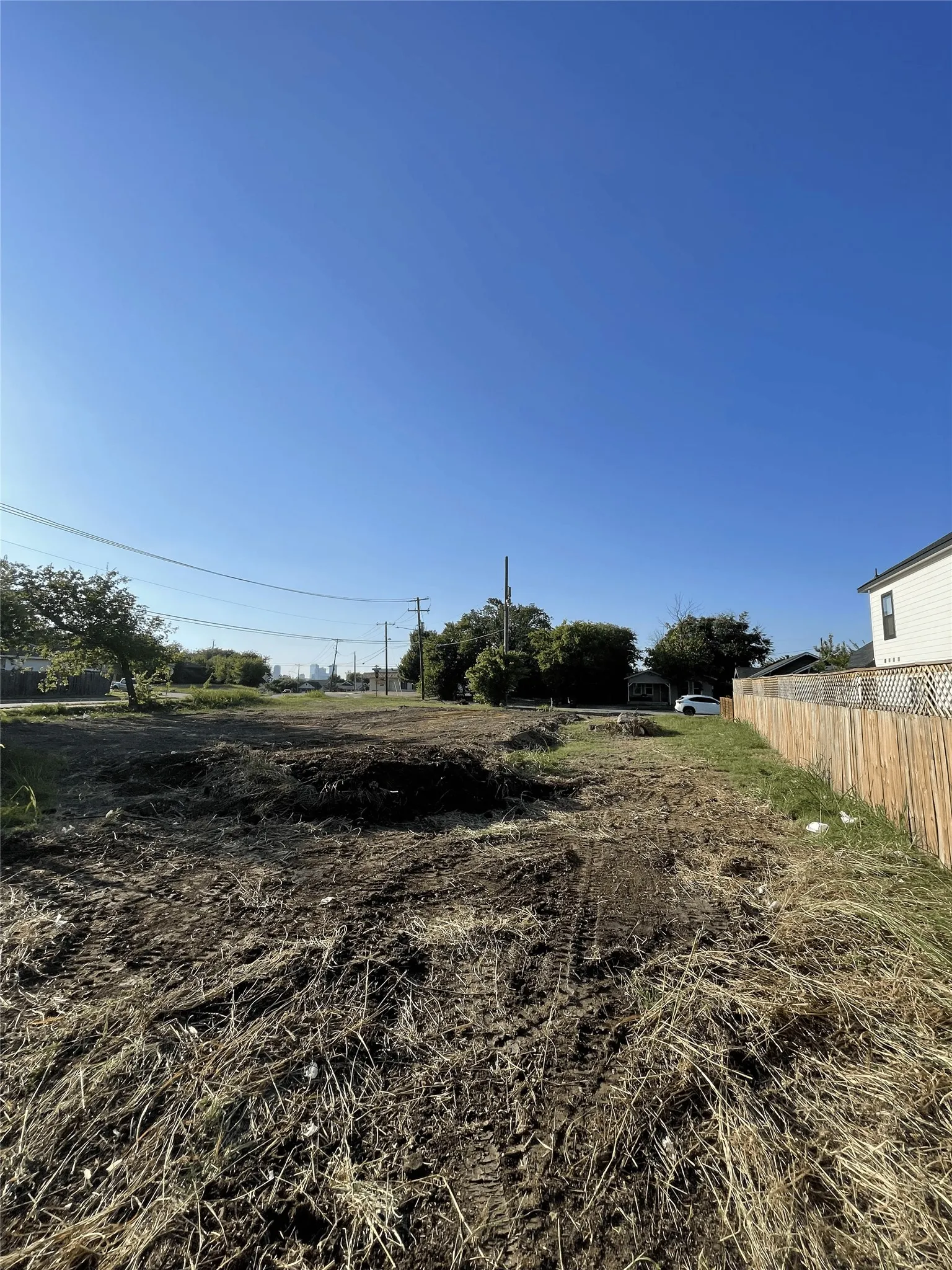 Cleared lot featuring a wood fence boundary, open sky, and visible street access