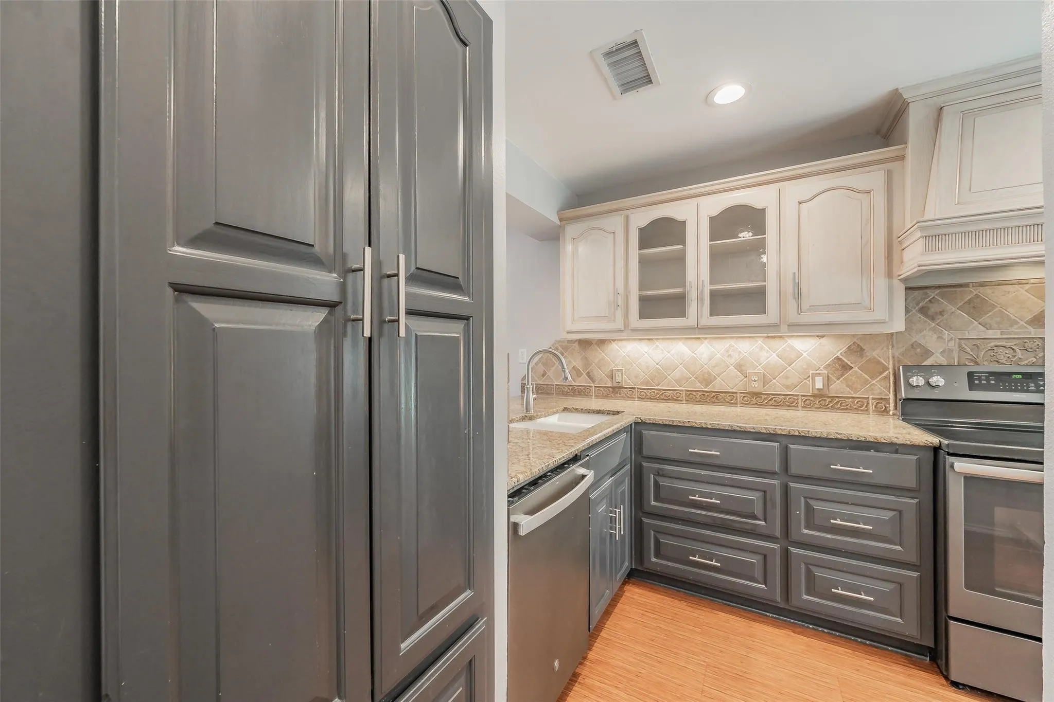 Kitchen featuring two-tone cabinetry, stone countertops, and a tiled backsplash