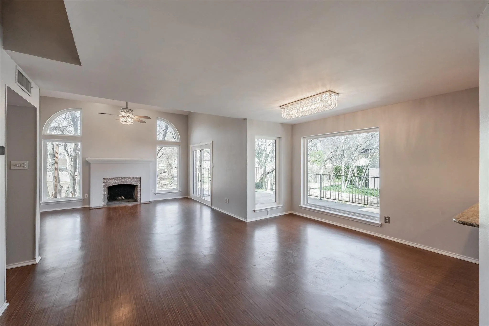 Spacious living area featuring wood-finish flooring, a brick fireplace with mantel, and vaulted ceilings