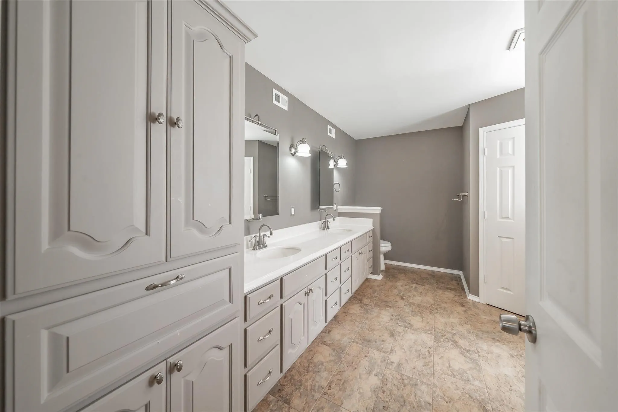 Spacious bathroom featuring a double vanity with ample storage cabinetry, dual sinks, and light-colored countertops