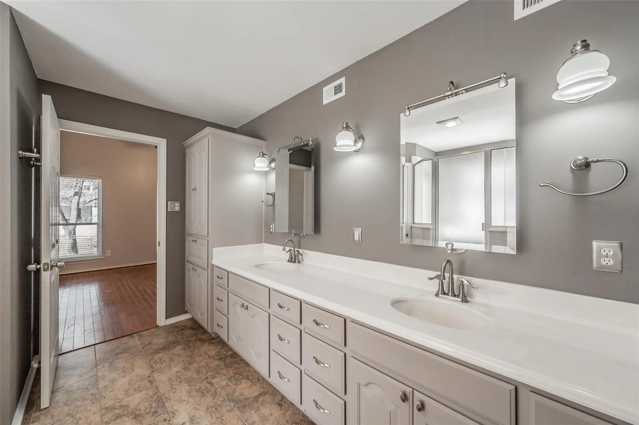 Bathroom featuring dual undermount sinks with brushed nickel fixtures, a white solid surface countertop, and extensive cabinetry