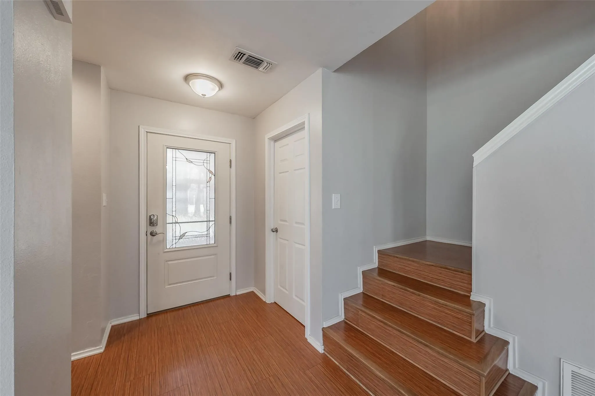 Entryway featuring wood-finish flooring, a white front door with decorative glass, and a flush-mount ceiling light