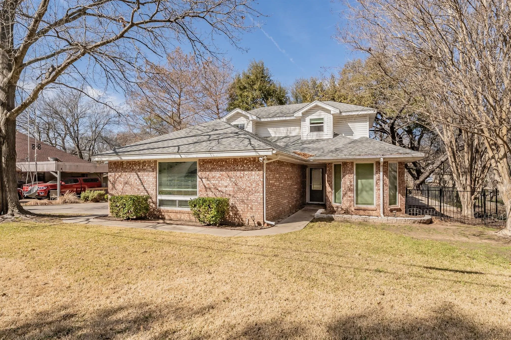 Traditional brick and siding exterior featuring dormer windows, a covered entry, and established landscaping