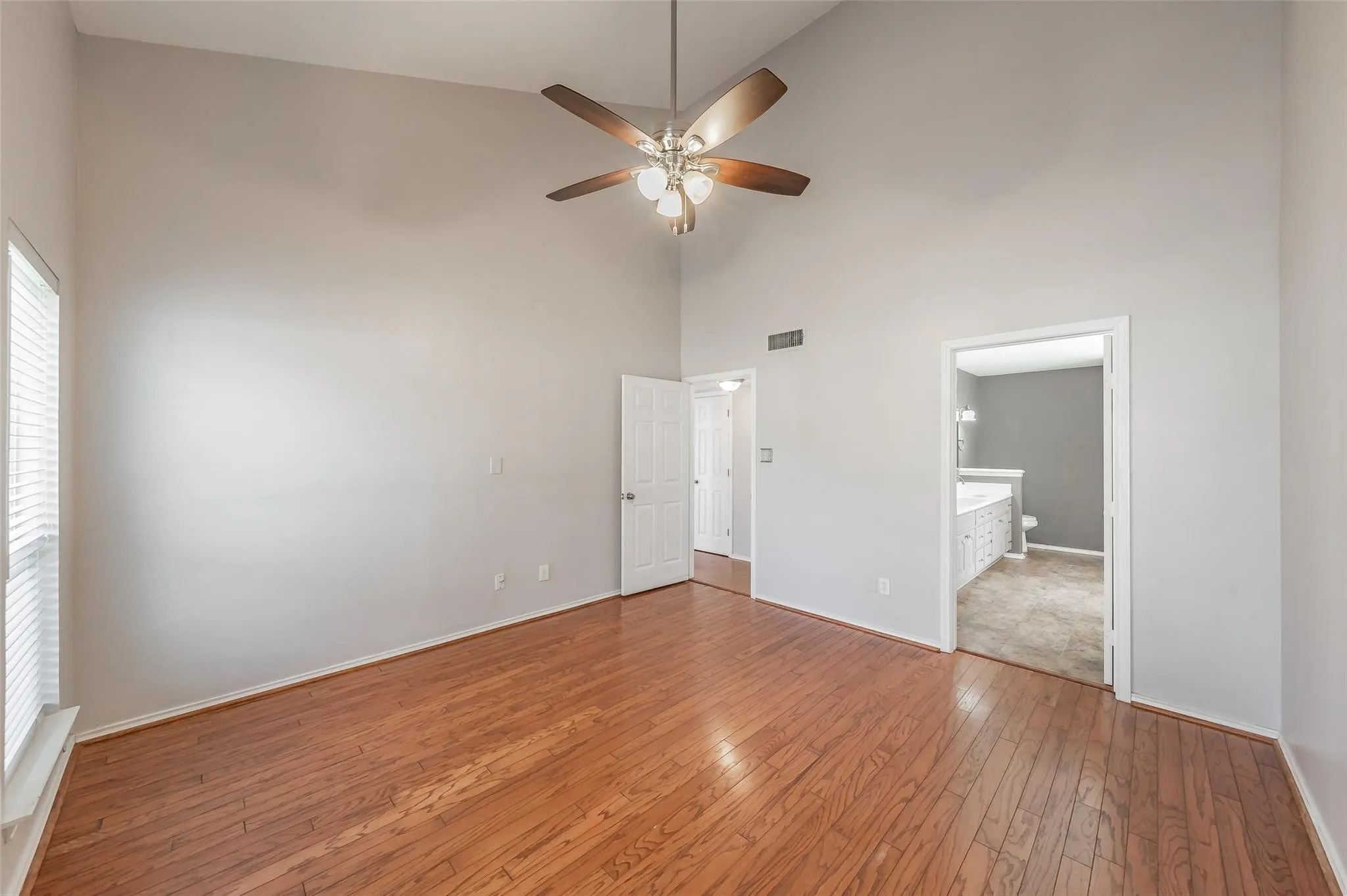 Spacious interior room featuring a vaulted ceiling and wood-finish flooring
