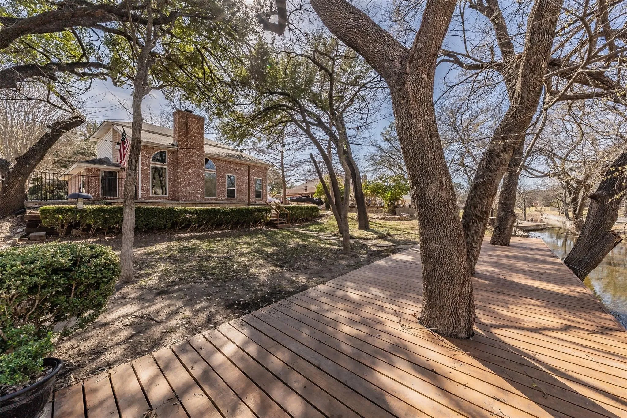 Waterfront property featuring a wood-finish dock with mature trees integrated into the design