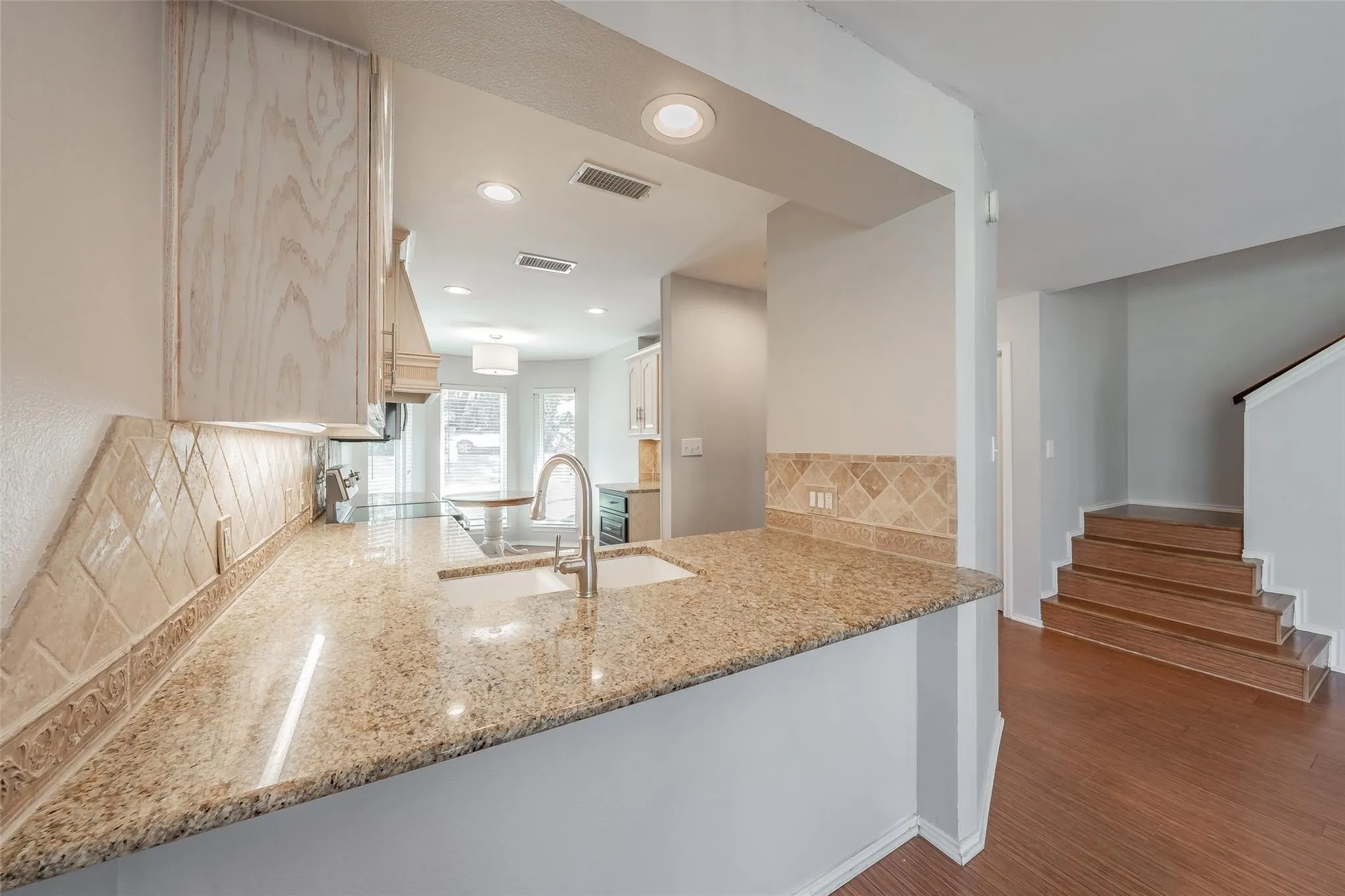 Kitchen counter with granite-finish countertop, undermount sink, and stainless steel faucet