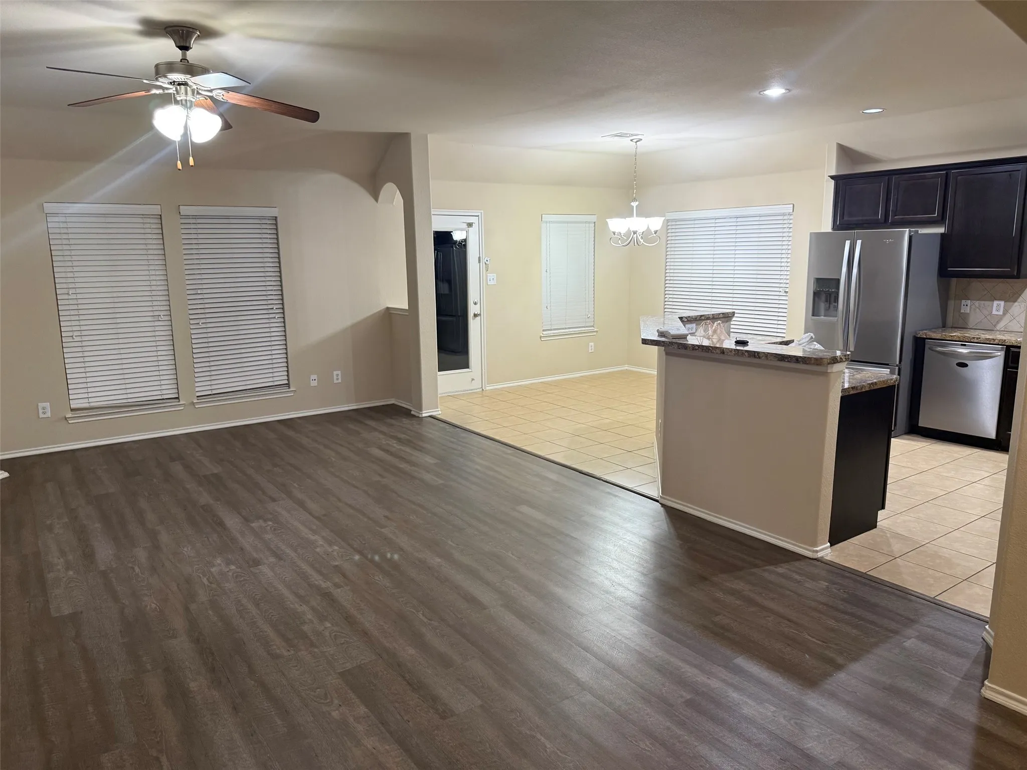 Spacious living area featuring wood-finish flooring and a ceiling fan with integrated lighting