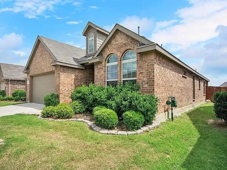 Brick exterior featuring an integrated garage, arched windows, and a dormer
