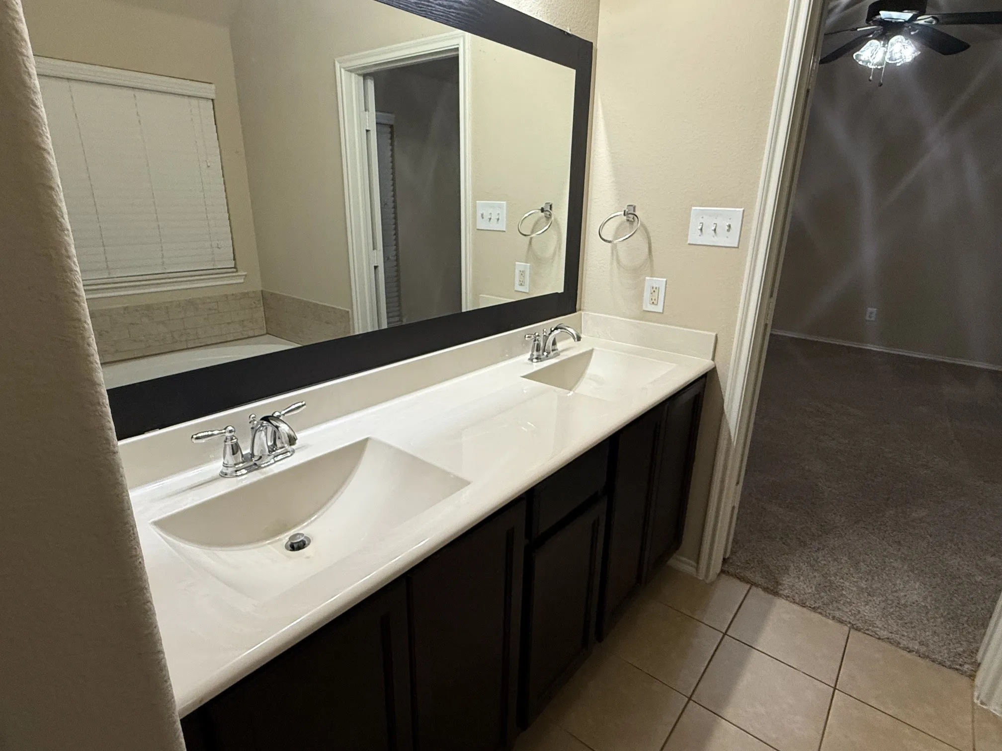Dual vanity with integrated sinks, chrome faucets, and dark wood-finish cabinetry