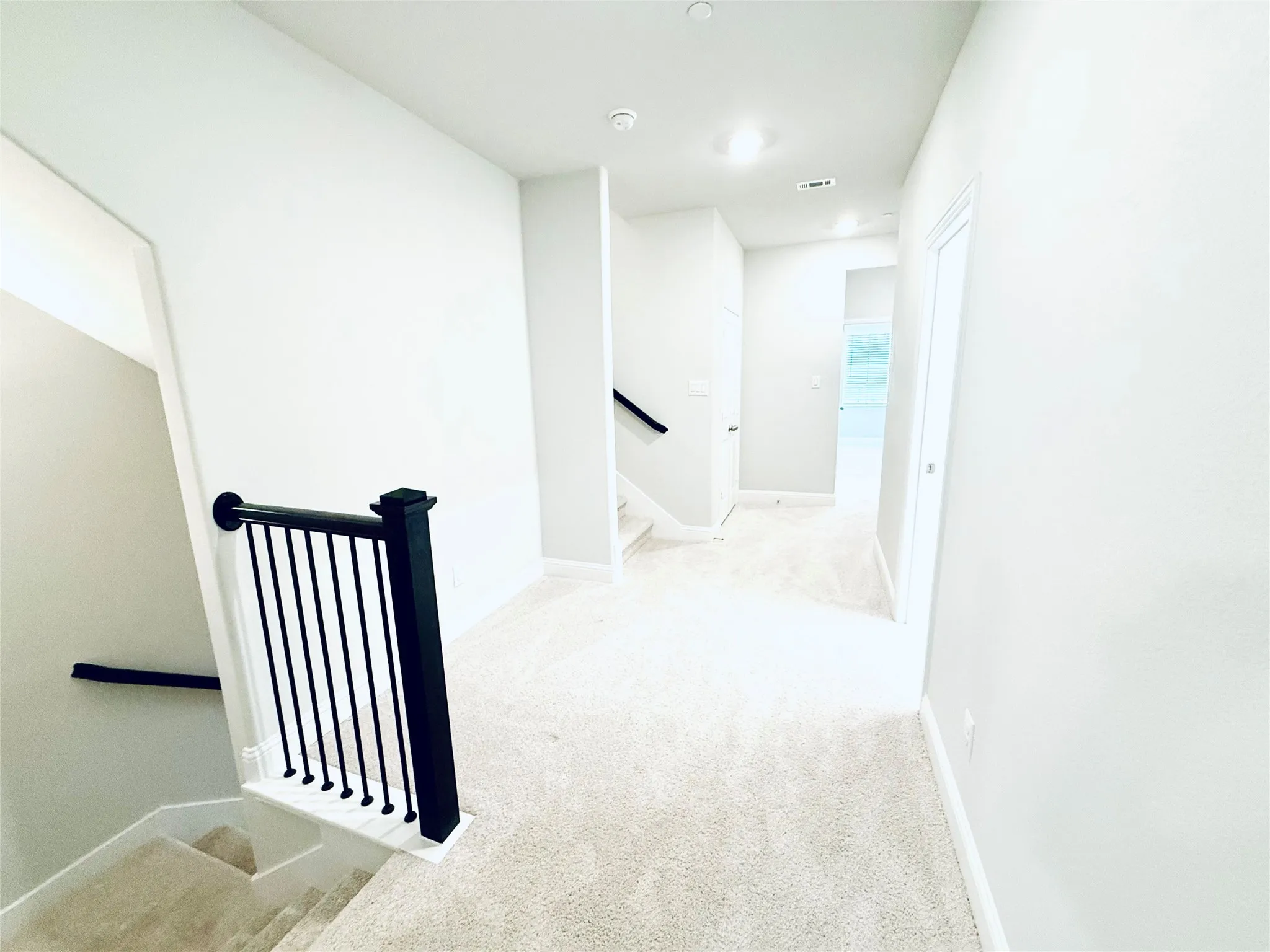Upper-level landing featuring light-toned carpeting and recessed lighting