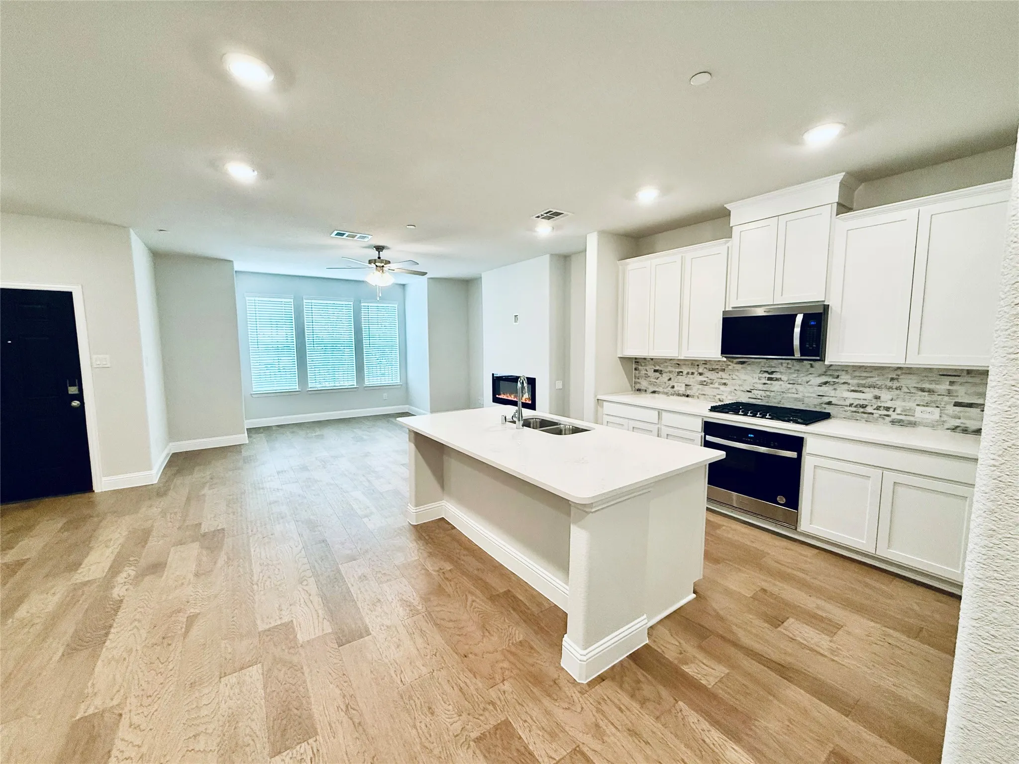 Open-concept living space featuring wood-finish flooring, recessed lighting, and a contemporary ceiling fan