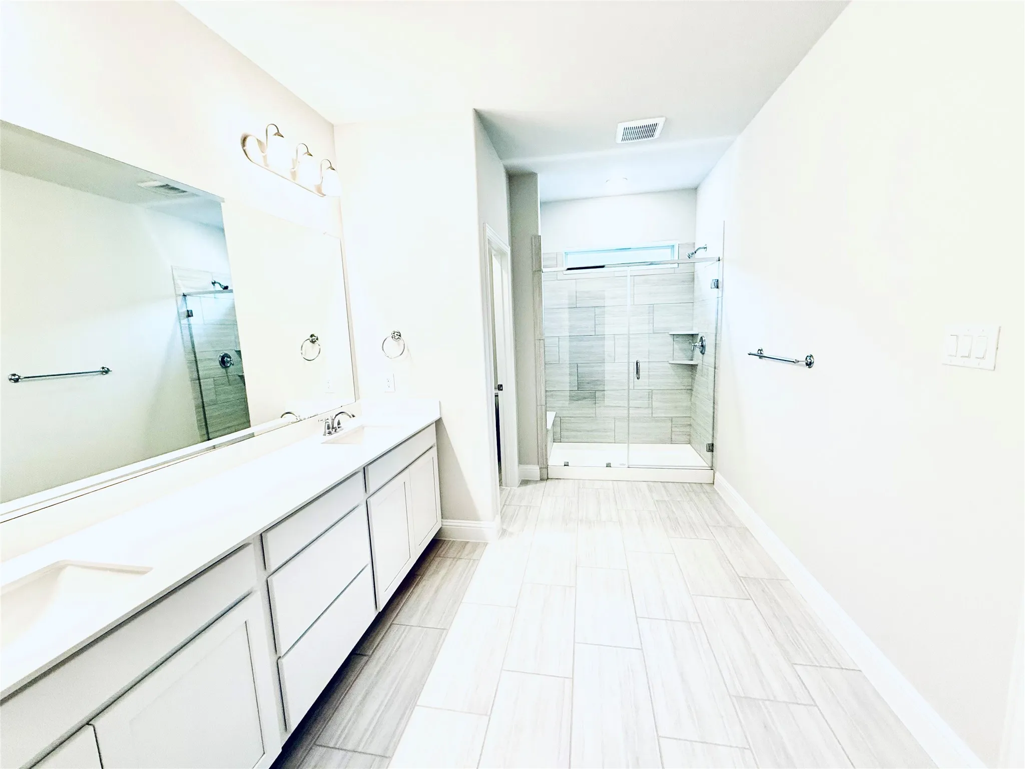 Modern bathroom featuring a spacious glass-enclosed shower with tile surround and built-in shelving