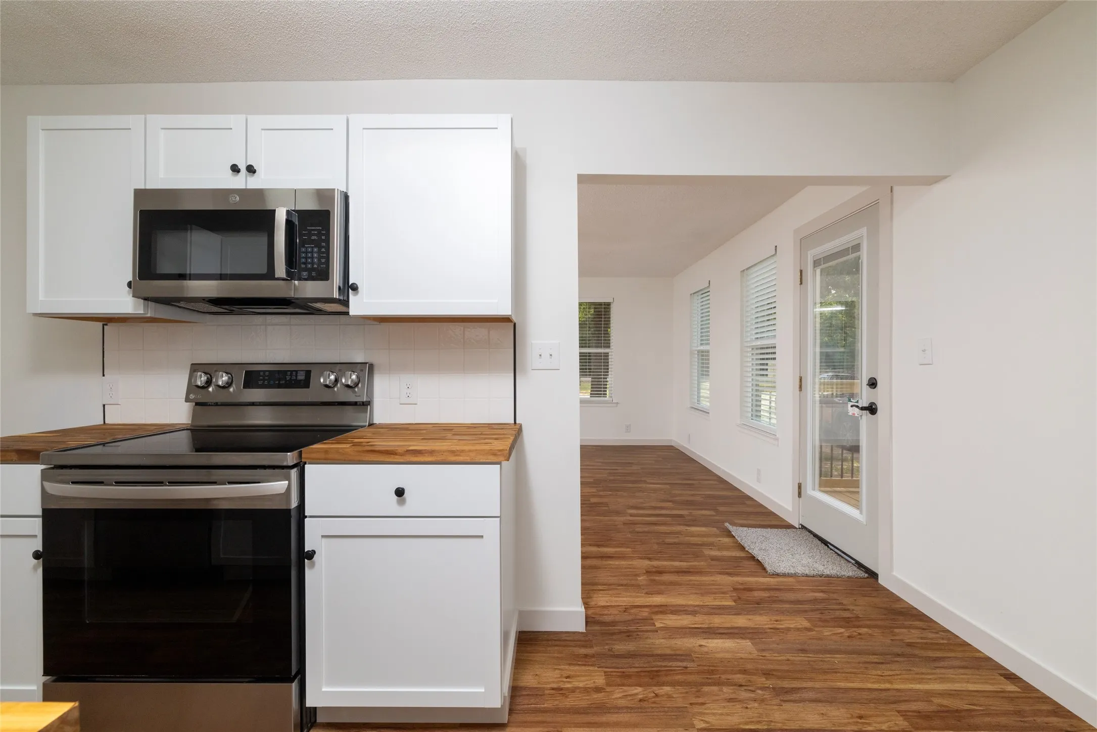 Kitchen featuring white shaker-style cabinetry, wood-finish countertops, stainless steel appliances, and a white subway tile backsplash