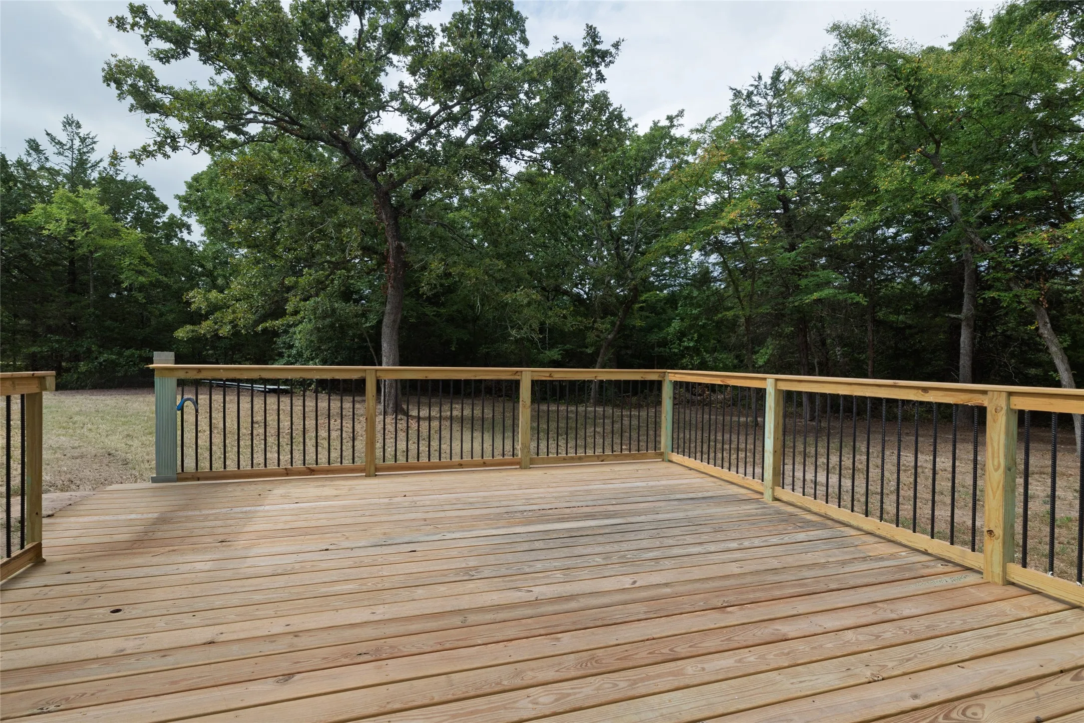 Spacious outdoor deck with natural wood flooring and black metal balusters