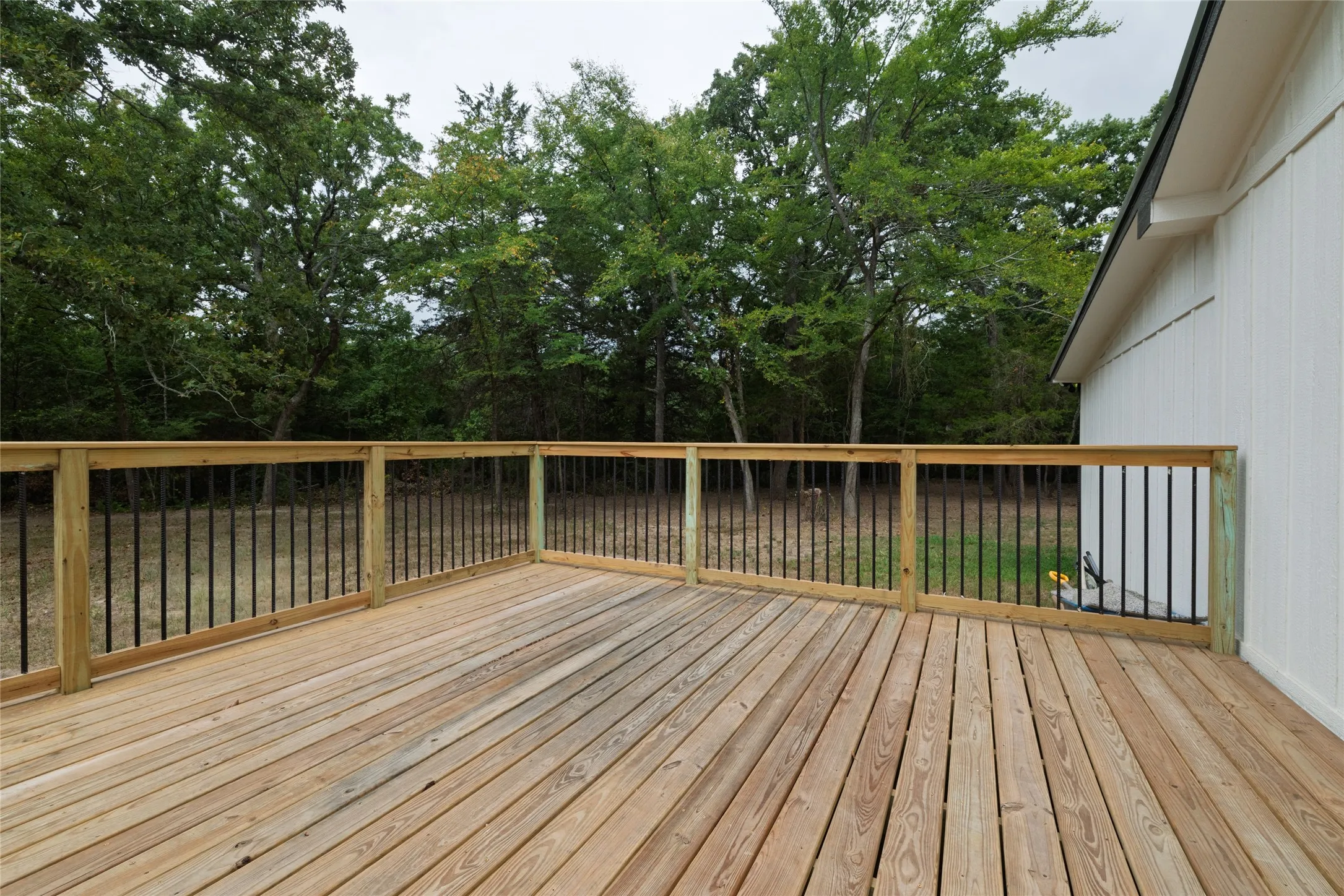 Expansive wood deck with a natural finish, featuring a wood railing with black metal balusters