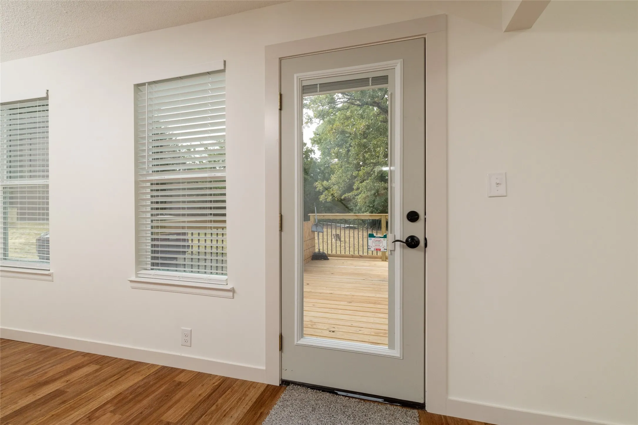 Full-light glass panel door opening to a wood deck