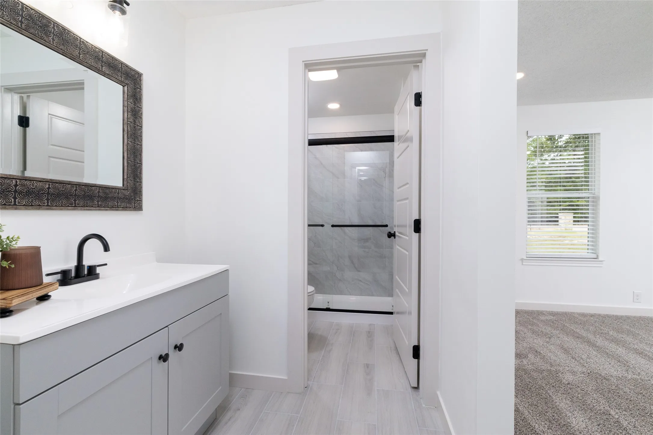 Bathroom vanity featuring a white countertop with integrated sink, matte black faucet, and a large framed mirror