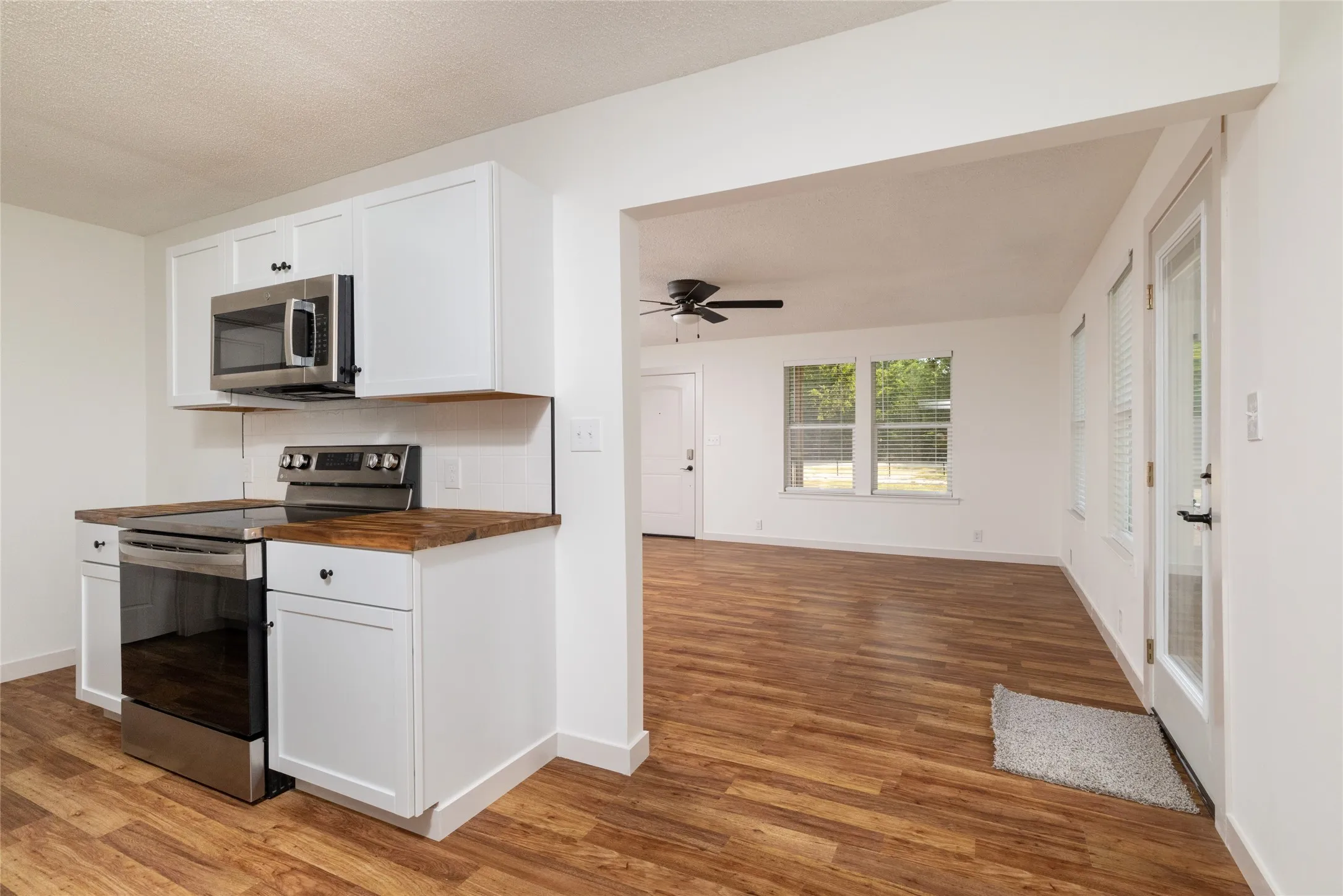 Kitchen area featuring white cabinetry, wood-finish countertops, and stainless steel appliances