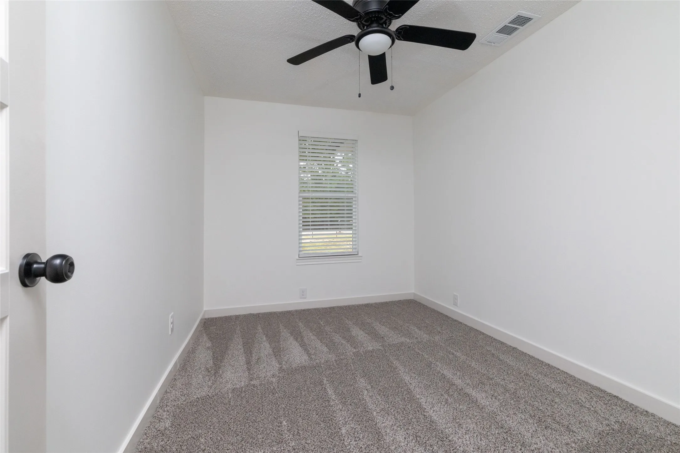 Room with neutral grey carpet, white walls, and a window with blinds
