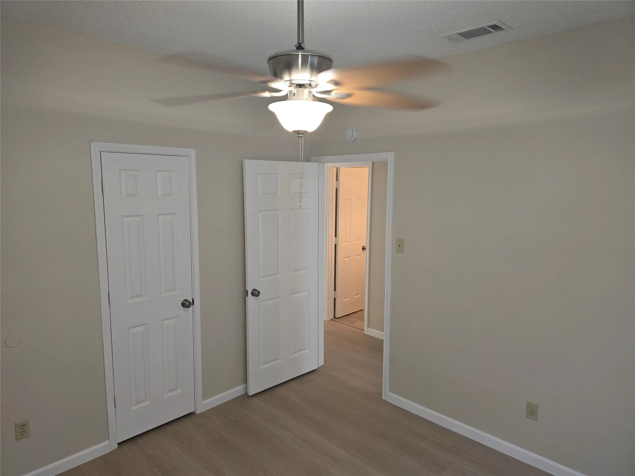 Room featuring wood-finish flooring, neutral wall tones, and white trim