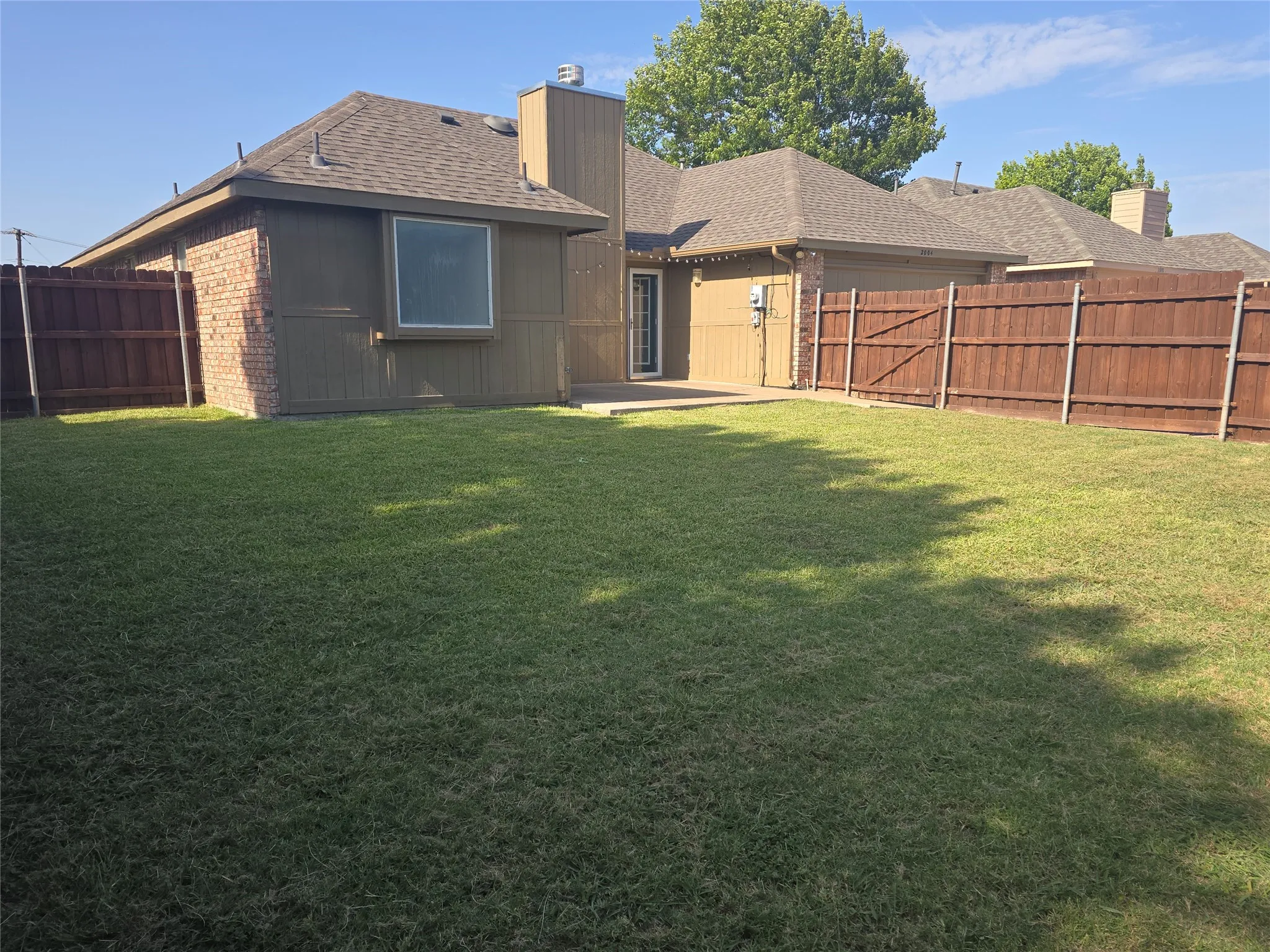 Expansive fenced backyard featuring a grassy lawn, a concrete patio, and a privacy fence