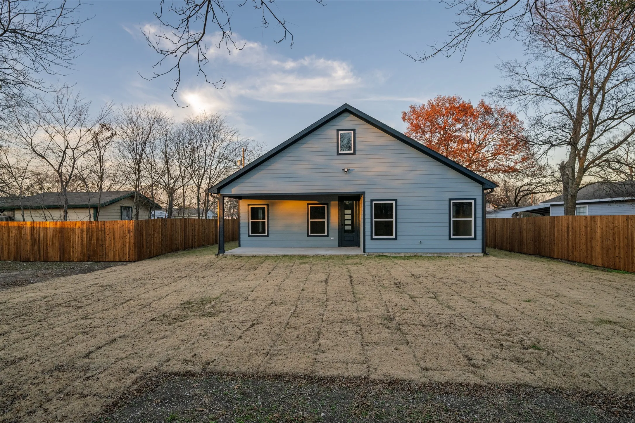 Light gray siding exterior with black trim, featuring an expansive backyard, covered patio, and a new privacy fence