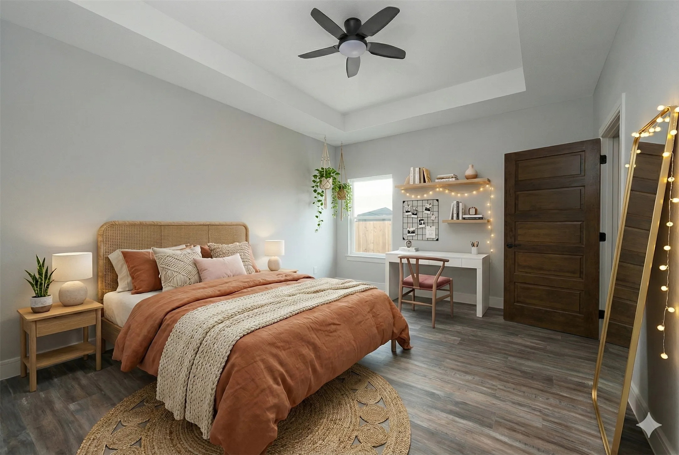 Spacious room featuring tray ceilings with a ceiling fan, wood-finish flooring, a dark wood paneled door, and built-in floating shelves