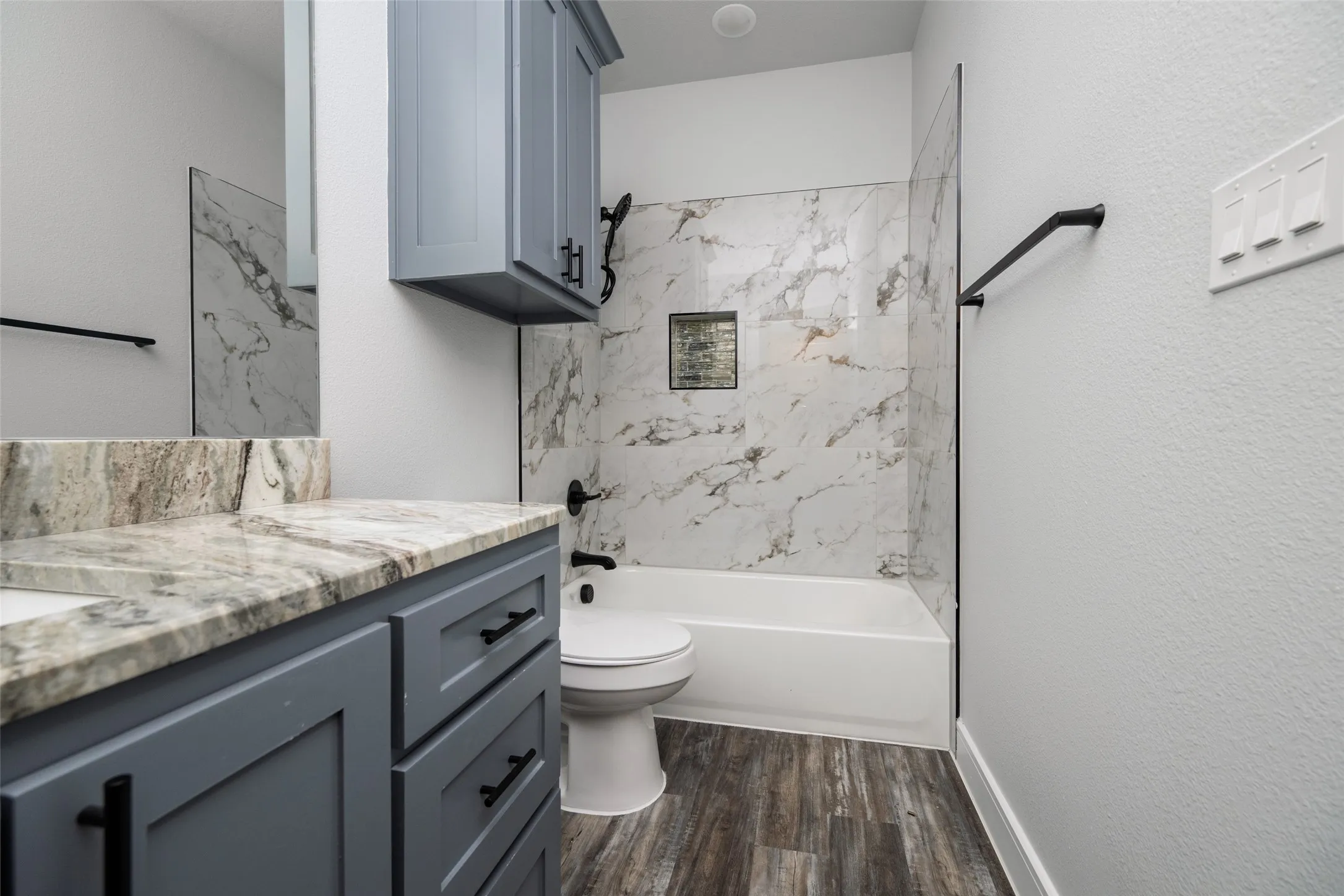 Bathroom featuring a modern vanity with light stone countertop, gray cabinetry, and matte black hardware