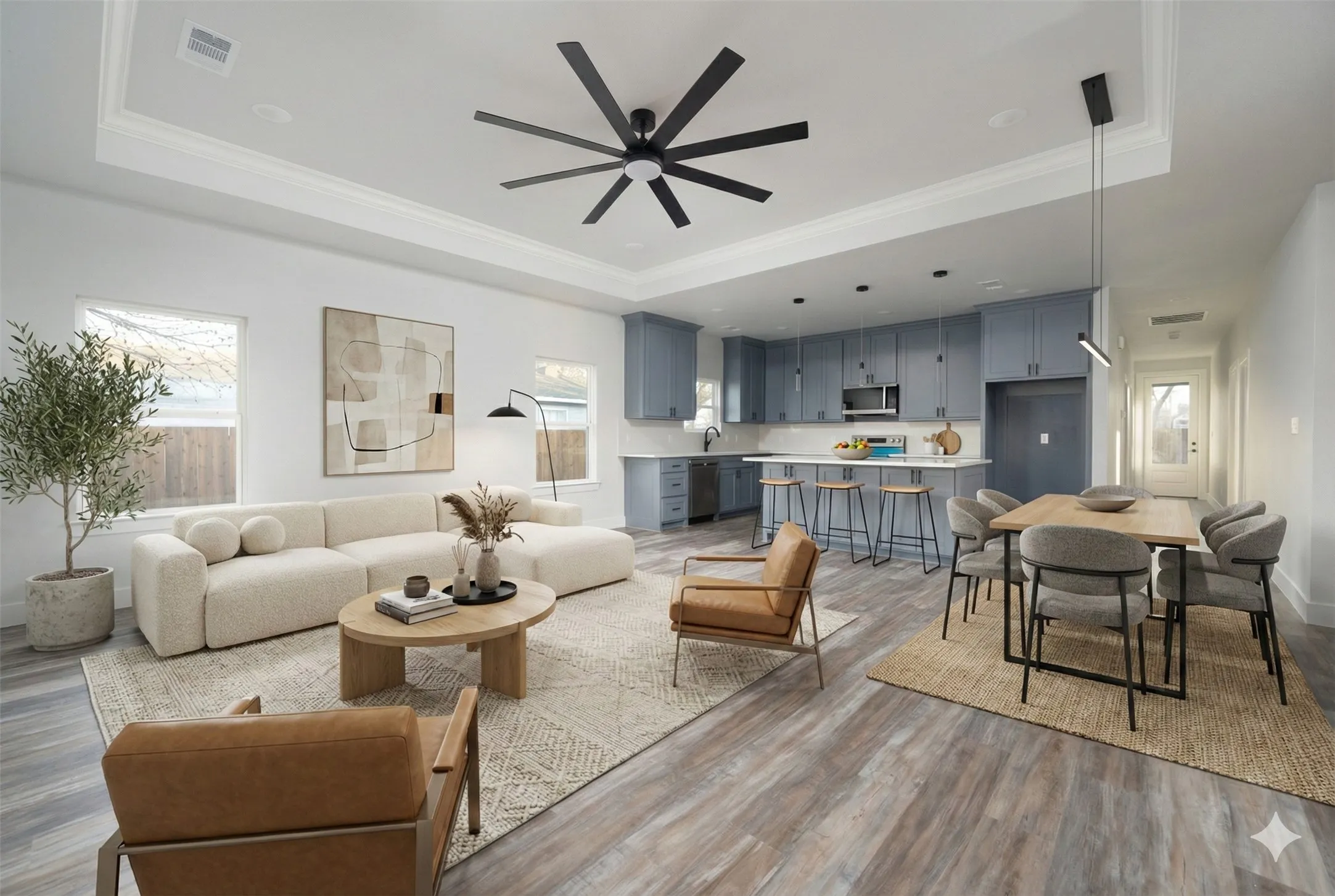 Open-concept living space featuring wood-finish flooring, a tray ceiling with crown molding, and recessed lighting