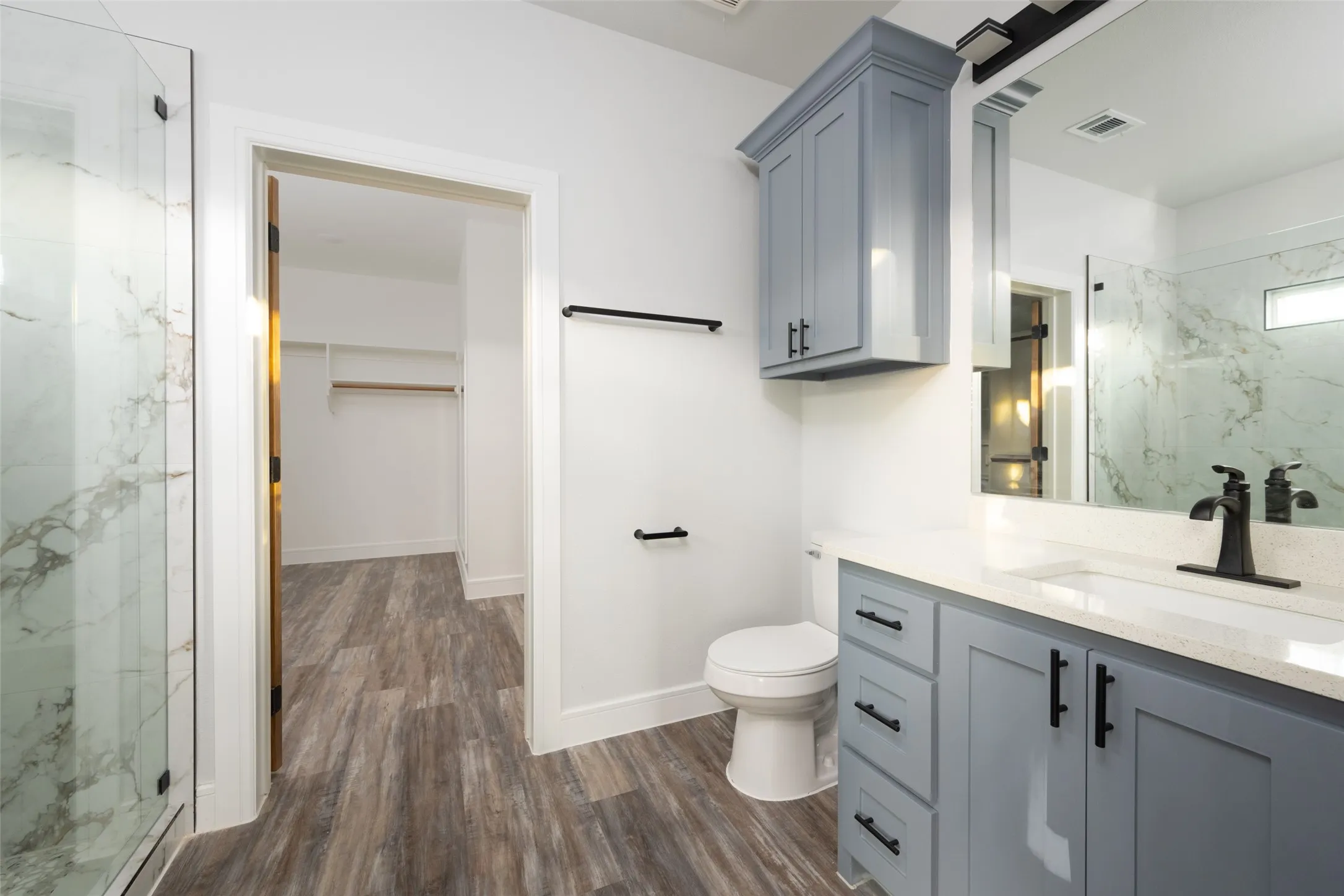 Bathroom featuring a blue vanity with a white countertop and rectangular sink, matte black faucet, and mirrored medicine cabinet