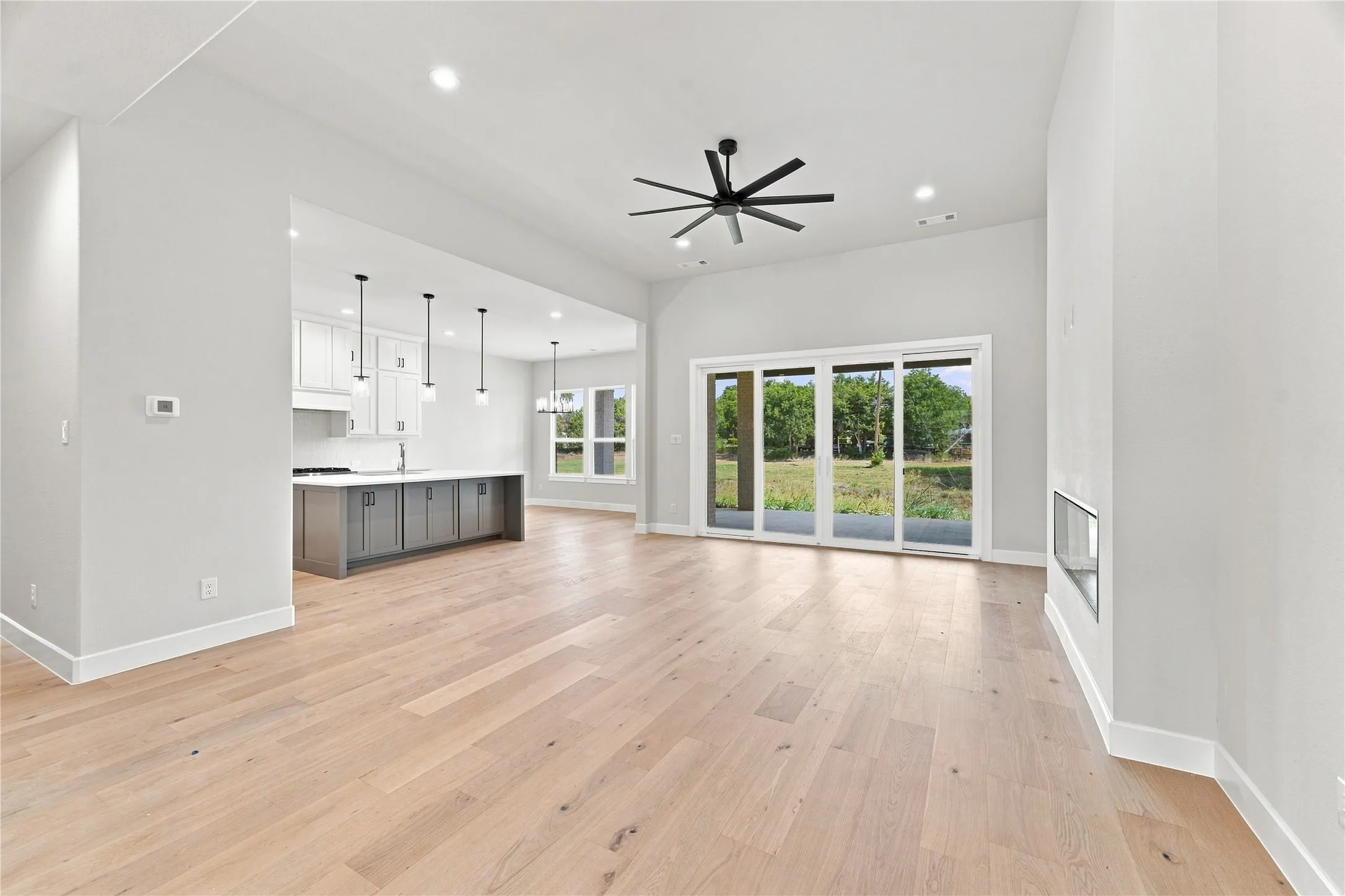 Spacious interior featuring wood-finish flooring, a contemporary ceiling fan, and recessed lighting