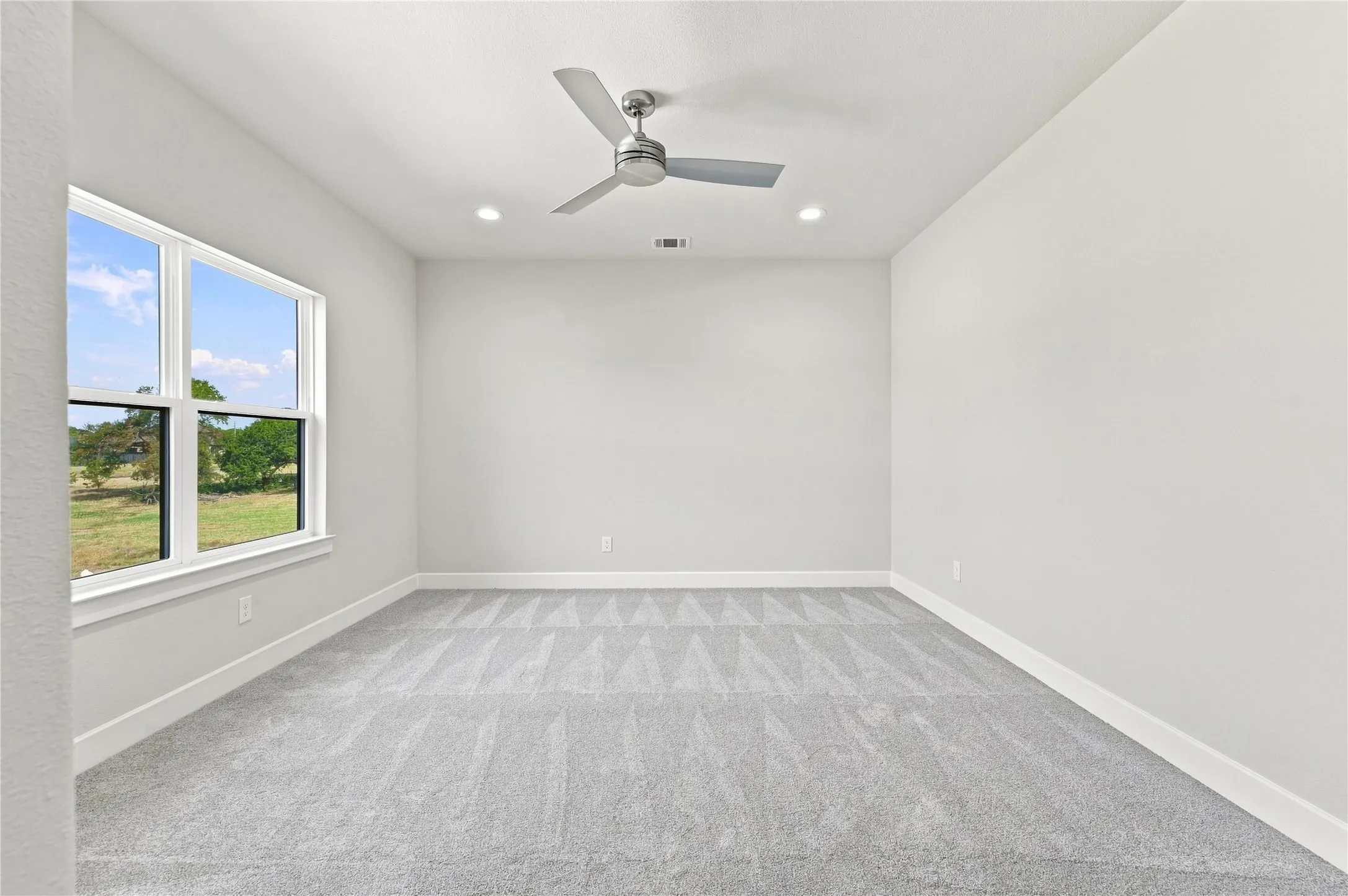 Neutral-toned walls, recessed lighting, and a ceiling fan create a comfortable atmosphere
