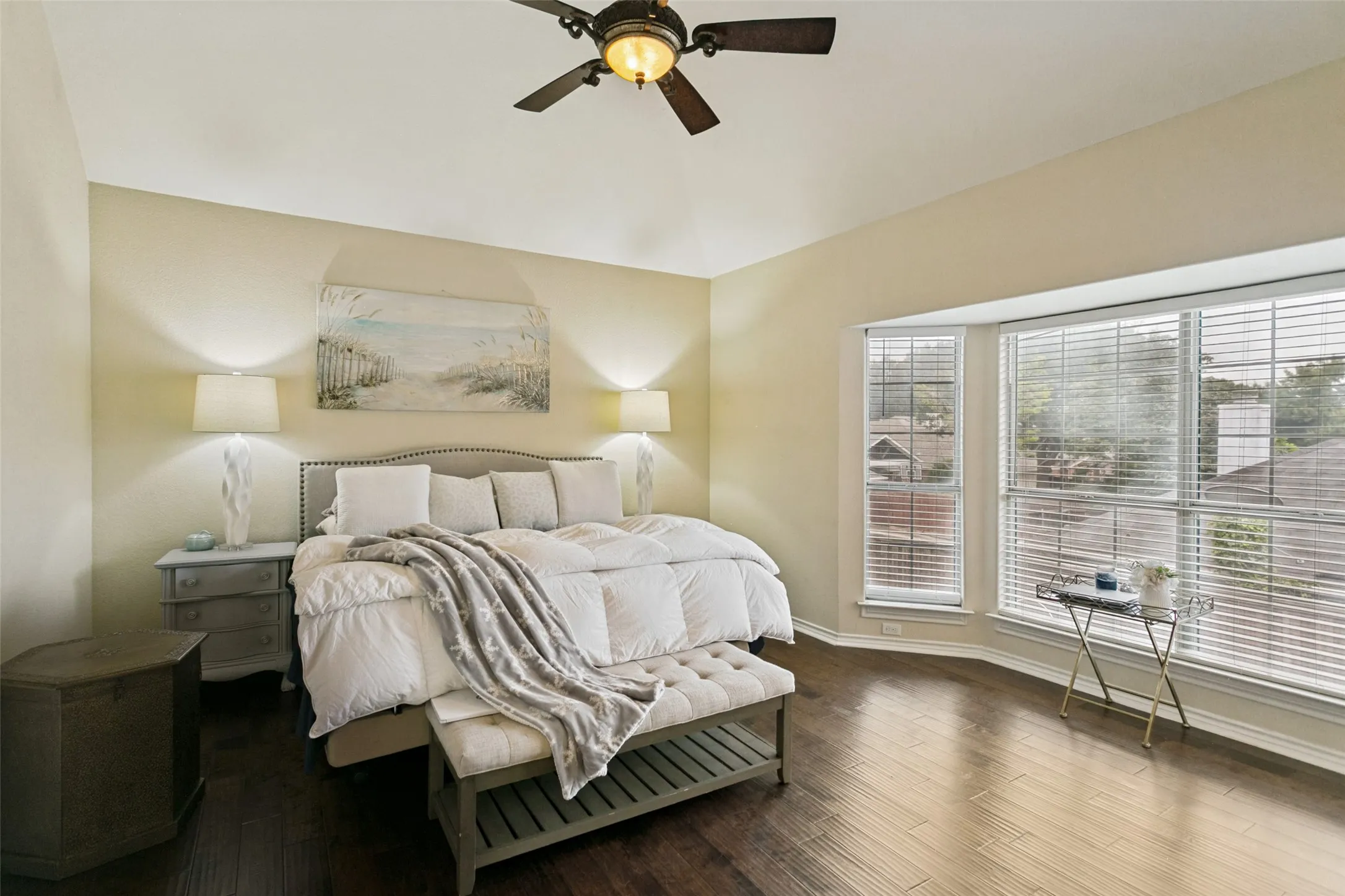 Spacious primary bedroom with large window and ceiling fan.