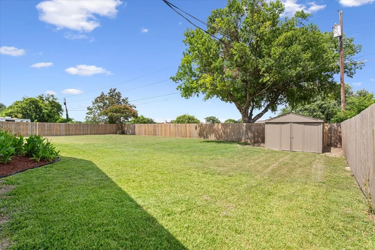 Expansive fenced backyard featuring a storage shed