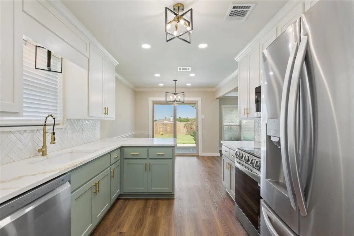 Kitchen featuring an LG stainless steel appliance package, two-tone cabinetry with gold-tone hardware, quartz countertops, herringbone tile backsplash, and luxury vinyl plank flooring