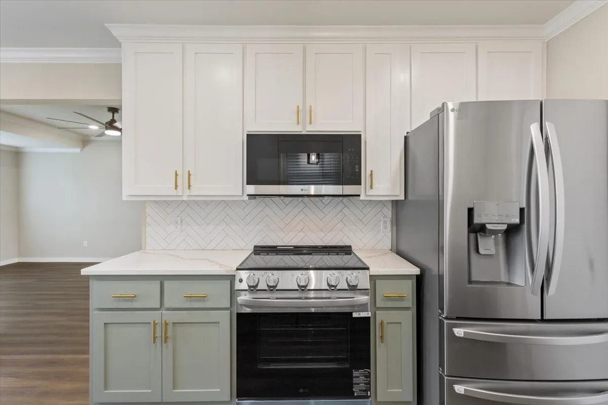 Modern kitchen featuring an LG stainless steel appliance package and white upper cabinetry with sage green lower cabinetry and gold-tone hardware