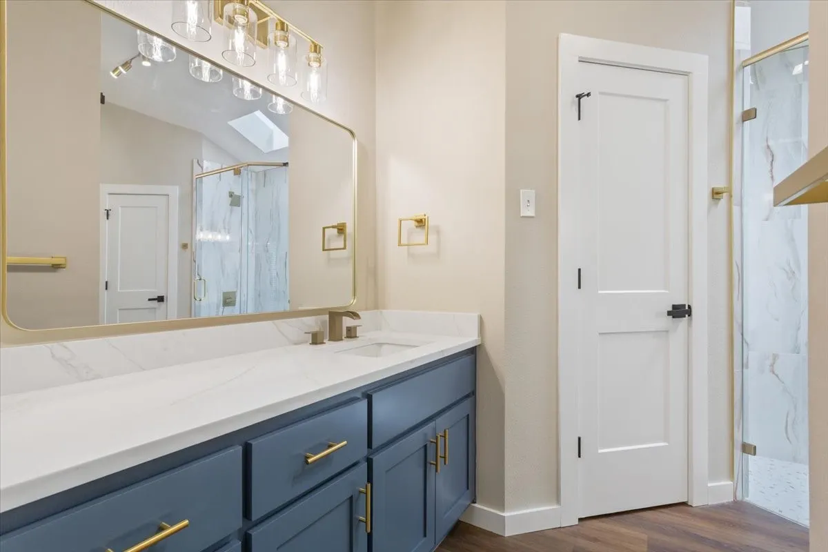 Primary, ensuite bathroom vanity featuring a white countertop, undermount sink, and blue cabinetry with gold-tone hardware