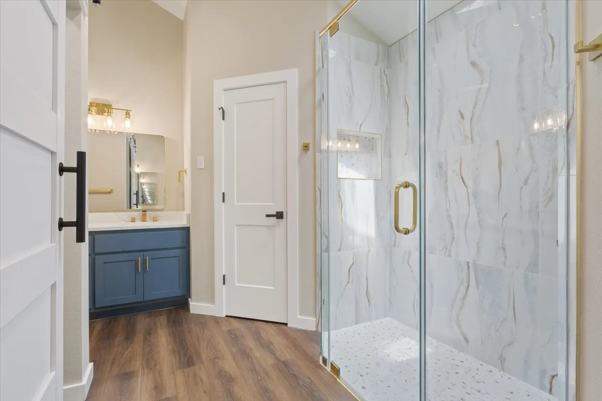 Walk-in shower with custom made glass enclosure, featuring light-toned large format tile walls and a textured shower pan